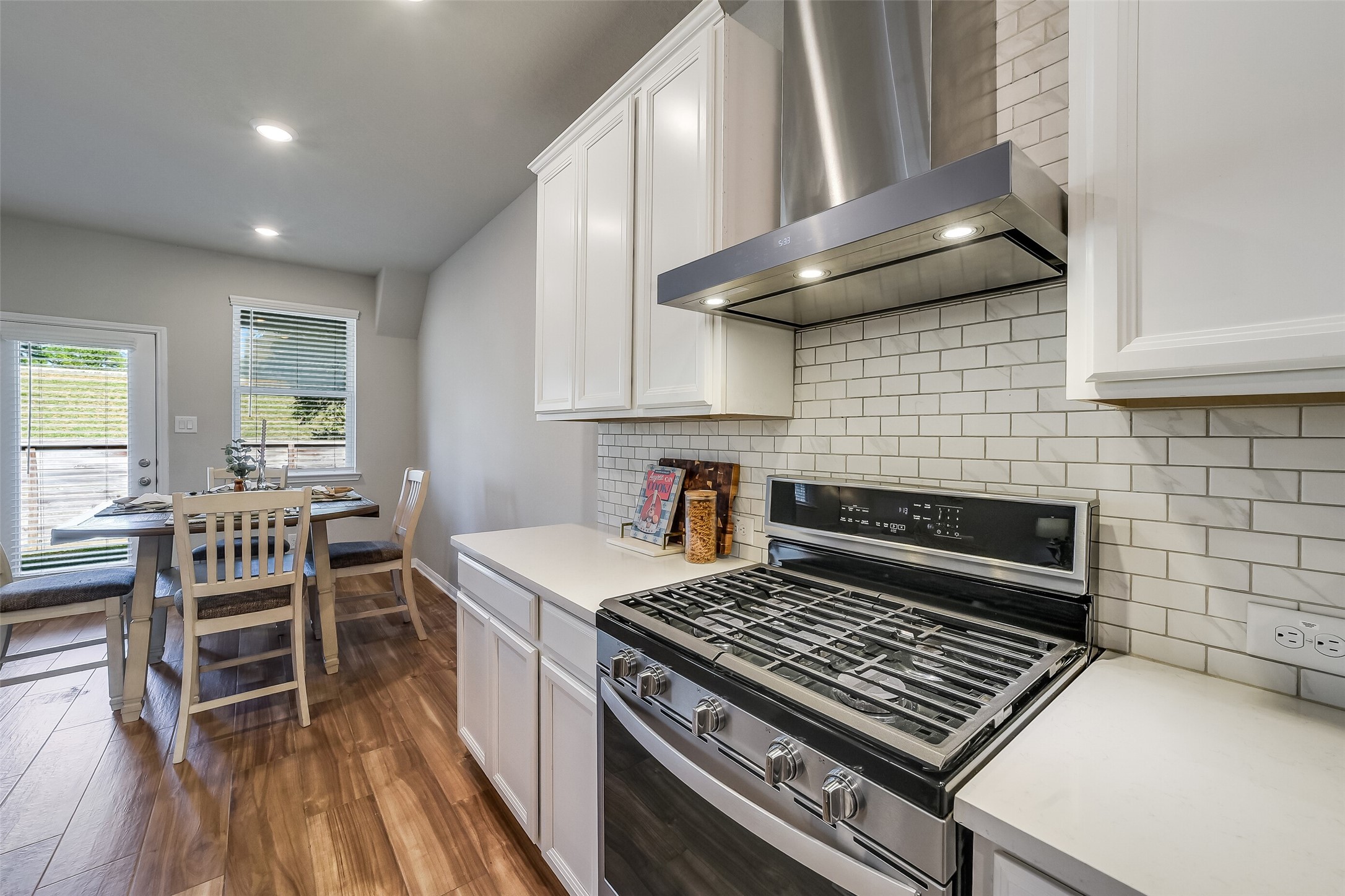 A gas range and a NEW stainless steel vent hood anchor the cooking area, with nearby counter space keeping meal preparation within easy reach. A gas range and a NEW stainless steel vent hood anchor the cooking area, with nearby counter space keeping meal preparation within easy reach.