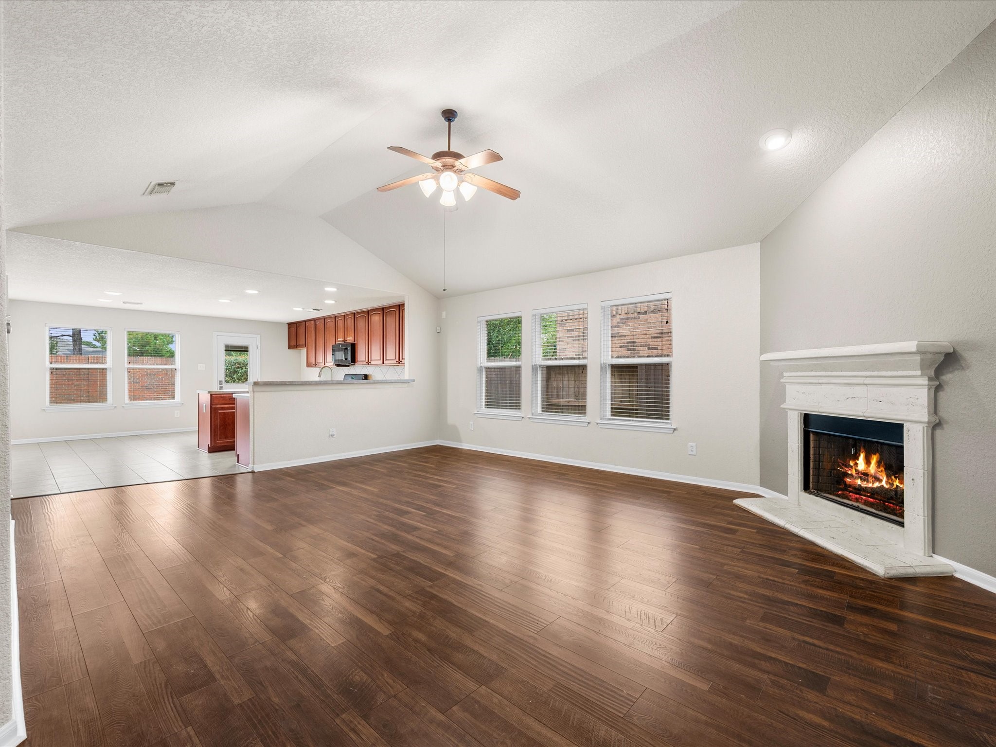 The open-concept living area provides the perfect gathering space with soaring ceilings, abundant natural light, and a cozy fireplace serving as the rooms focal point.