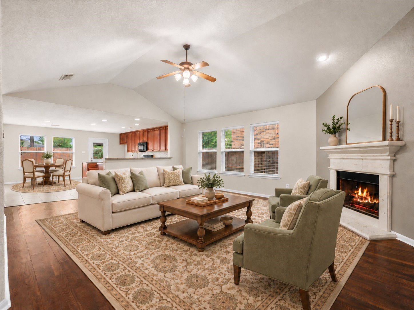 Furnishings have been virtually added to showcase the possibilities of this open-concept living area, where soaring ceilings, abundant natural light, and a cozy fireplace create a welcoming gathering space.