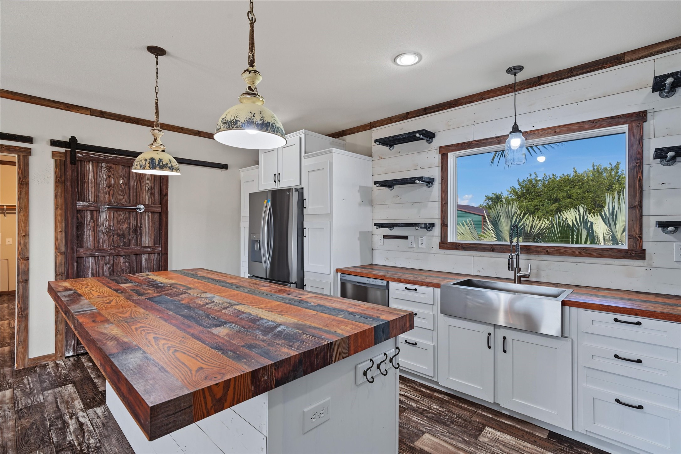 View of those magnificent countertops. The barn door leads into the pantry. The large window over the apron sink maximizes natural lighting in the kitchen. Plenty of storage in these cabinets