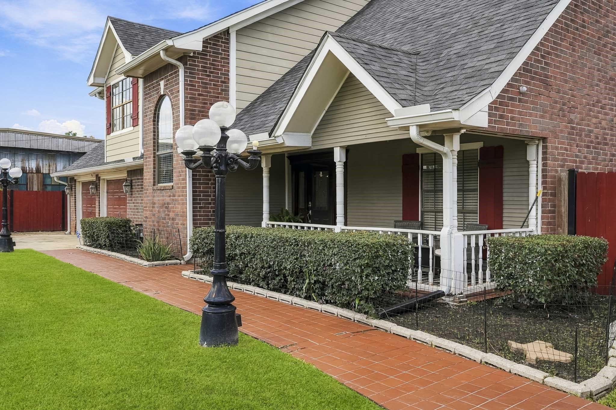 Charming two-story home with a classic brick facade, inviting front porch, and manicured landscaping, featuring elegant lamp posts lining the walkway. Charming two-story home with a classic brick facade, inviting front porch, and manicured landscaping, featuring elegant lamp posts lining the walkway.