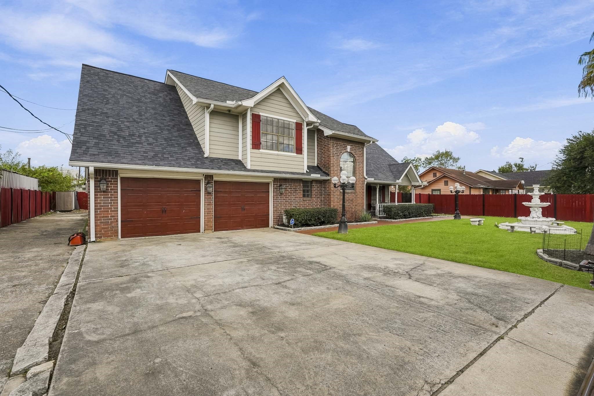Spacious two-story brick home with a three-car garage, charming front porch, and manicured lawn featuring a decorative fountain. Spacious two-story brick home with a three-car garage, charming front porch, and manicured lawn featuring a decorative fountain.