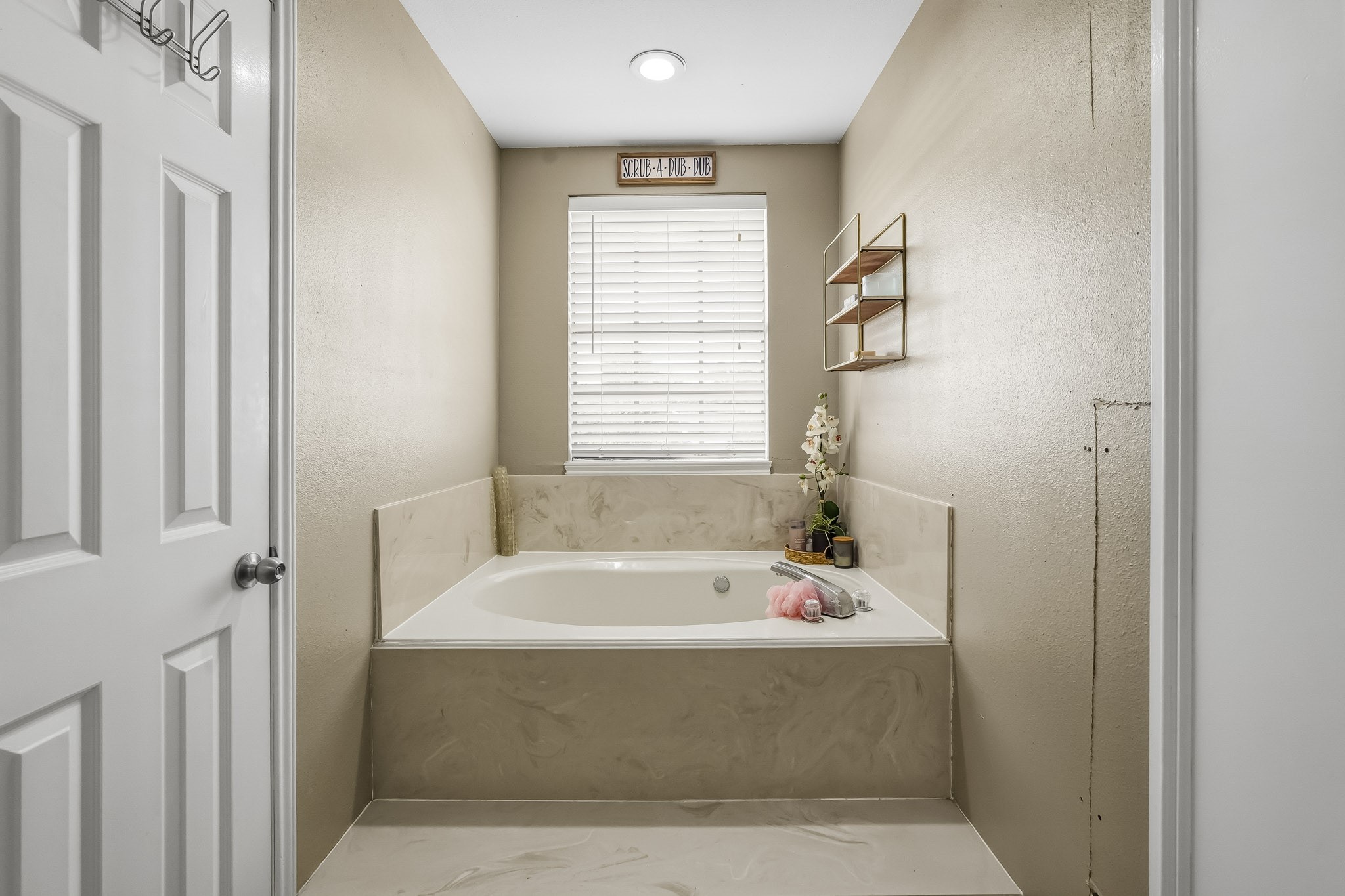 Relax in this serene bathroom featuring a spacious soaking tub set against neutral walls, with a window providing soft natural light.