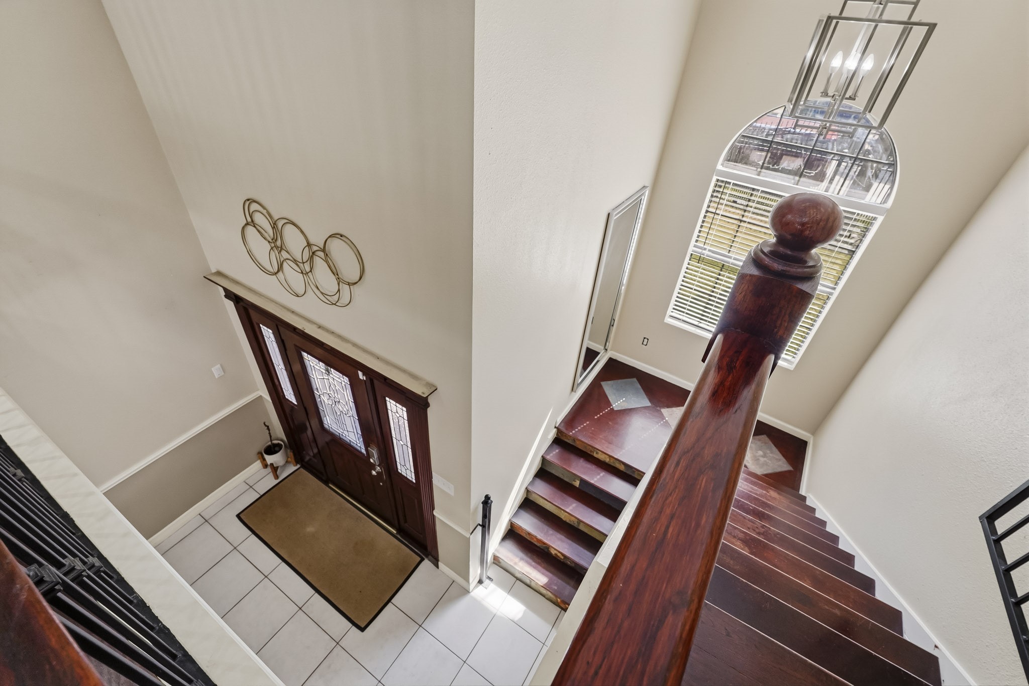 Elegant entryway with a grand staircase, featuring rich wood accents and abundant natural light from a large arched window.