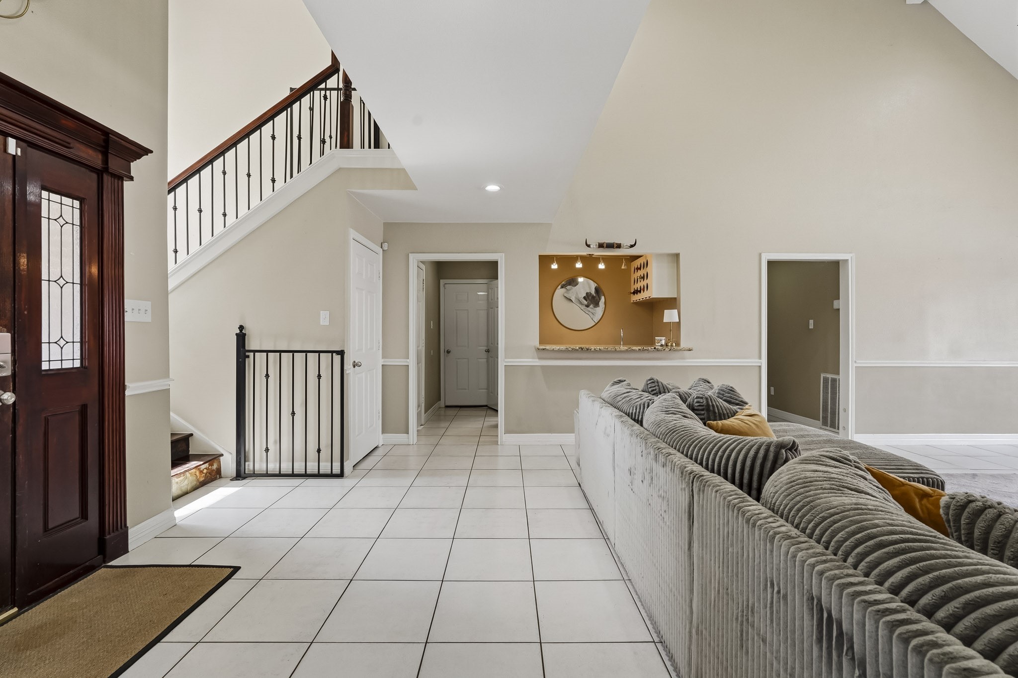 Spacious living area featuring high ceilings, elegant staircase, and a cozy lounge with plush seating, perfect for entertaining or relaxing.