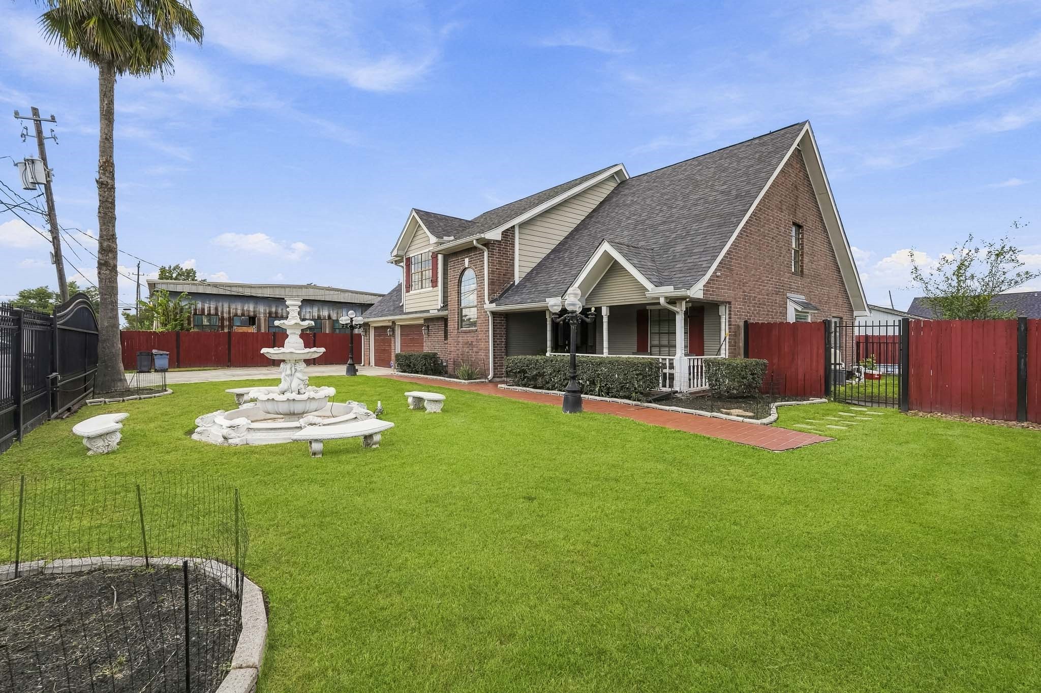 Charming brick home with a spacious yard, featuring a decorative fountain and a red brick pathway leading to the front entrance.