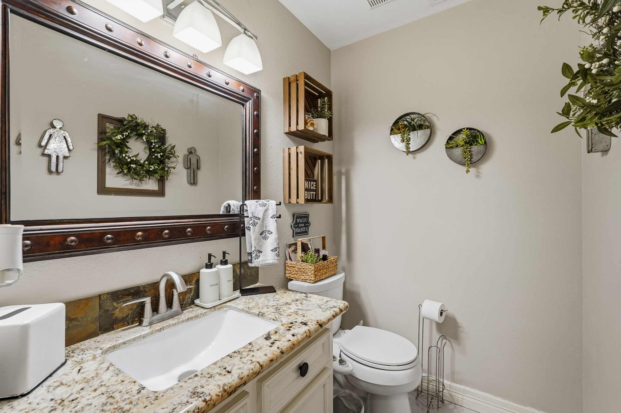 Charming half bathroom with a granite countertop, elegant mirror, and stylish decor.