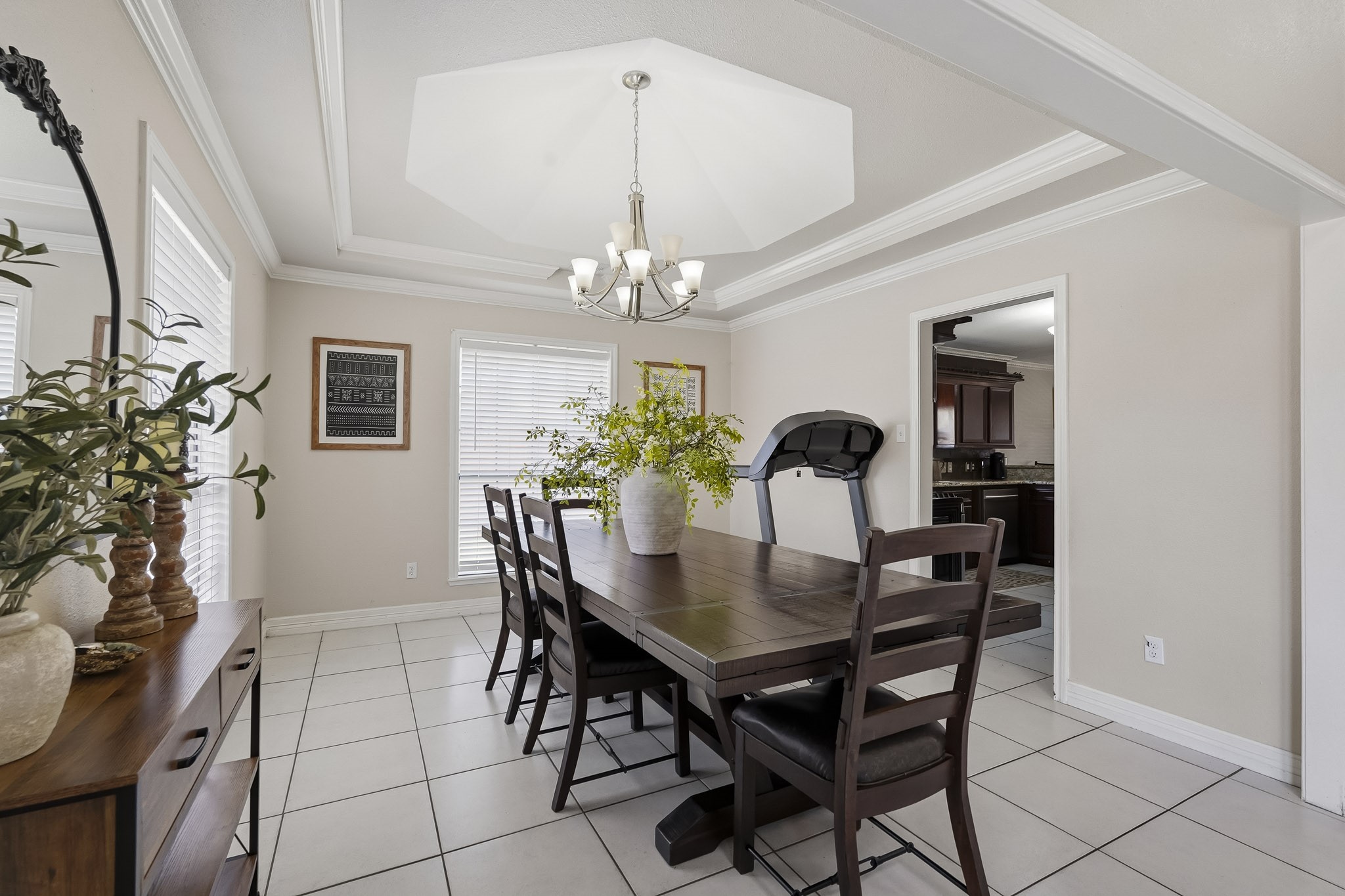 Elegant dining room featuring a spacious table, modern chandelier, and abundant natural light from large windows, perfect for gatherings.