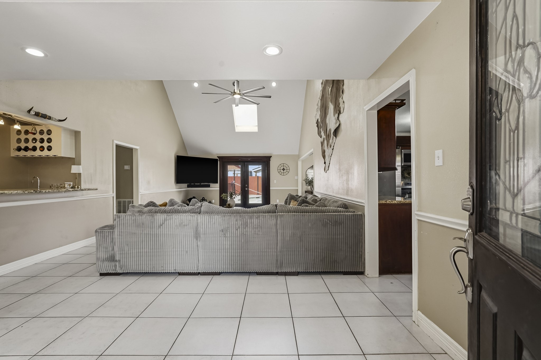 Spacious living area with high ceilings and abundant natural light from the skylight. The open layout connects to the wet bar area, perfect for entertaining. Spacious living area with high ceilings and abundant natural light from the skylight. The open layout connects to the wet bar area, perfect for entertaining.