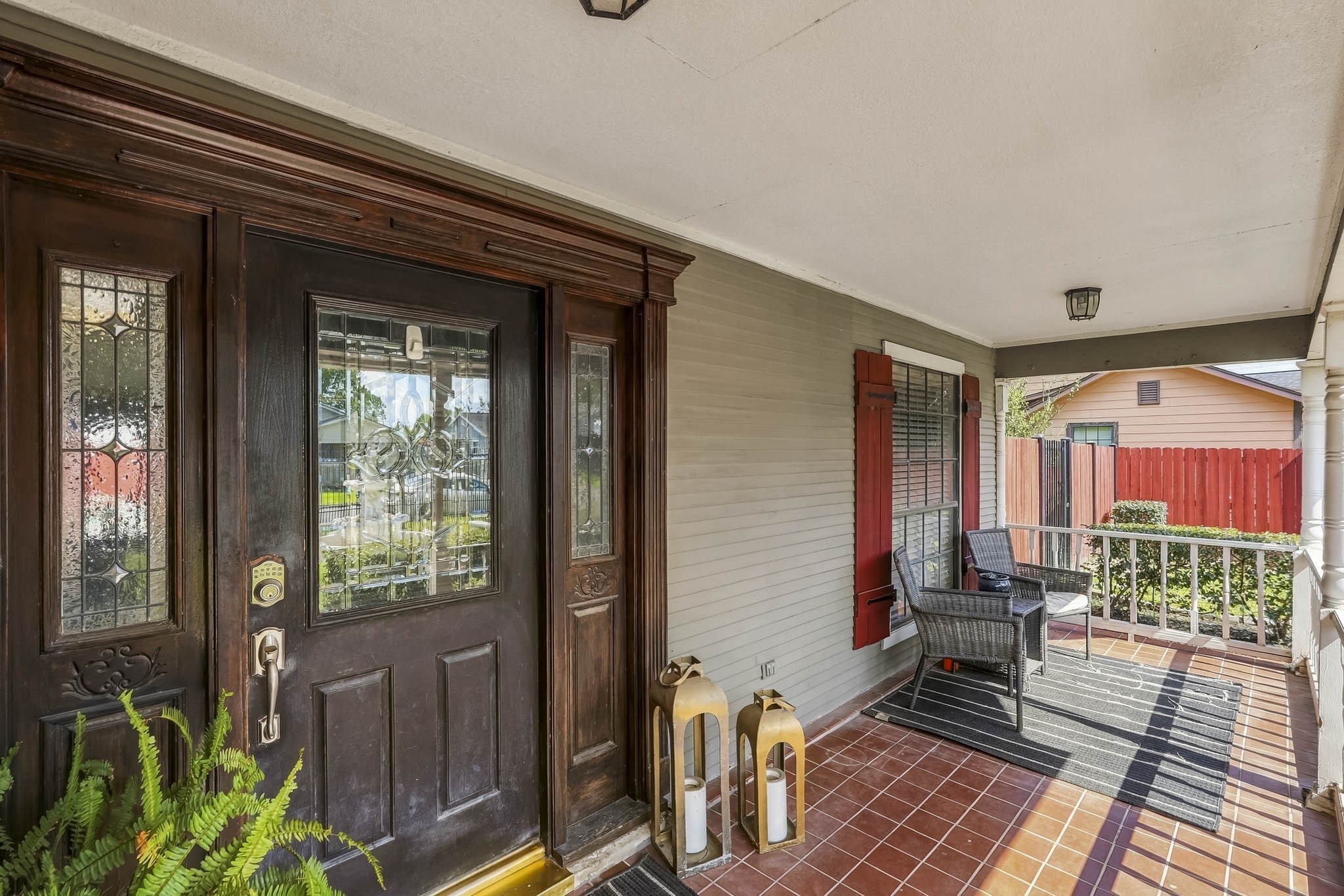 Charming front porch with elegant wood door, intricate glass panels, and cozy sitting area, perfect for welcoming guests. Charming front porch with elegant wood door, intricate glass panels, and cozy sitting area, perfect for welcoming guests.