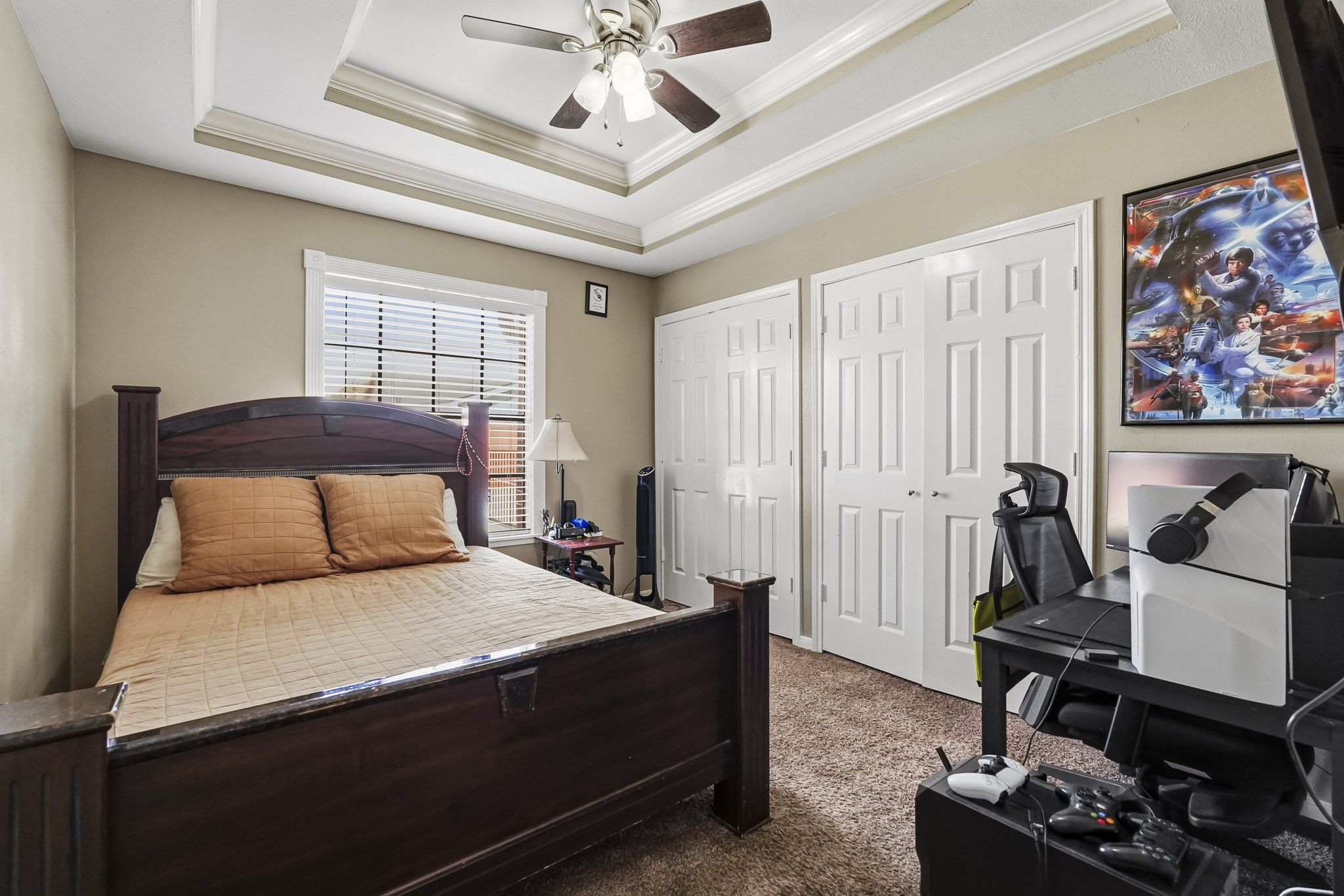 Cozy fourth bedroom with a tray ceiling and fan.