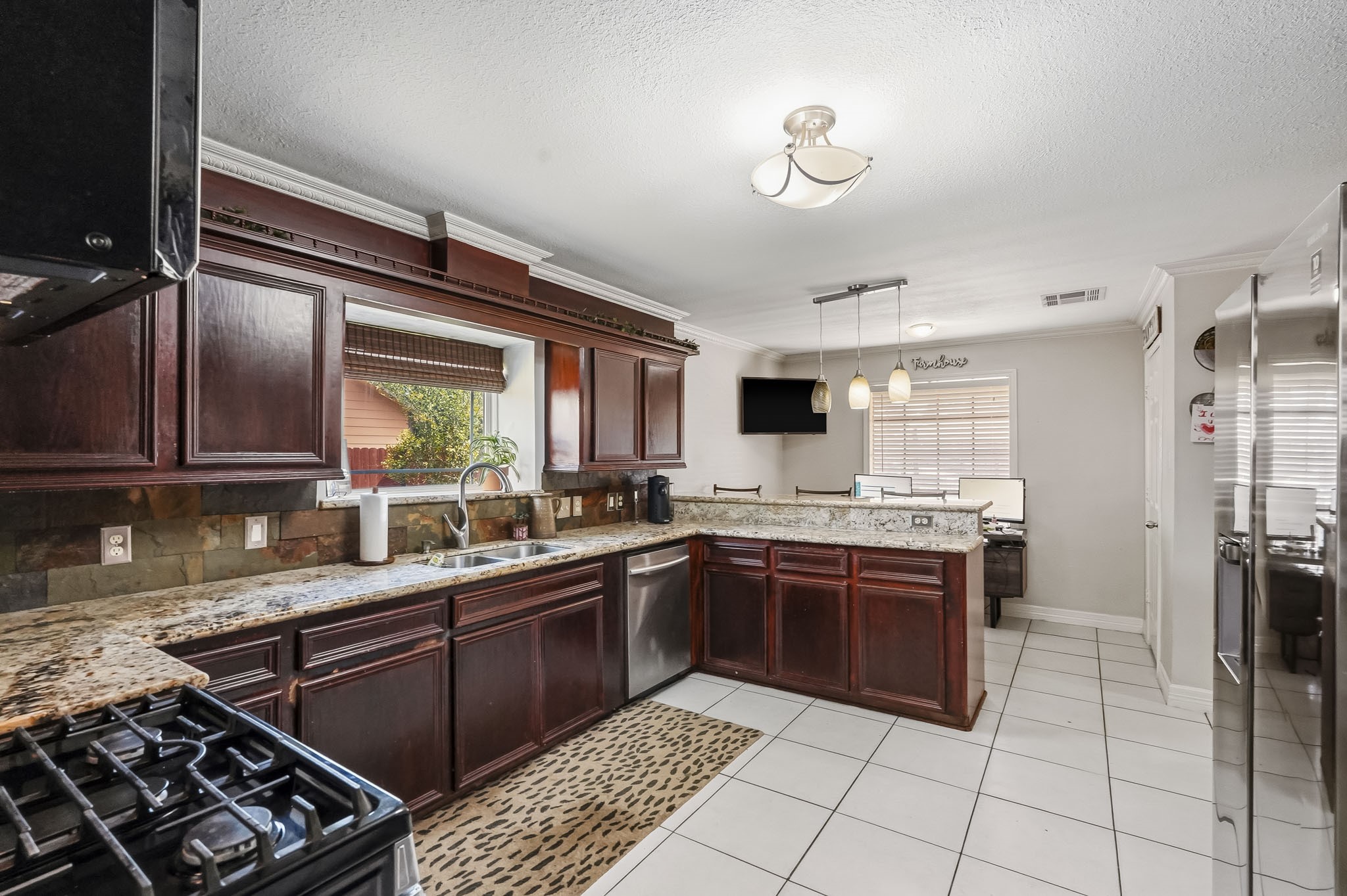 Spacious kitchen with rich wood cabinetry, granite countertops, and modern stainless steel appliances, offering a perfect blend of style and functionality.
