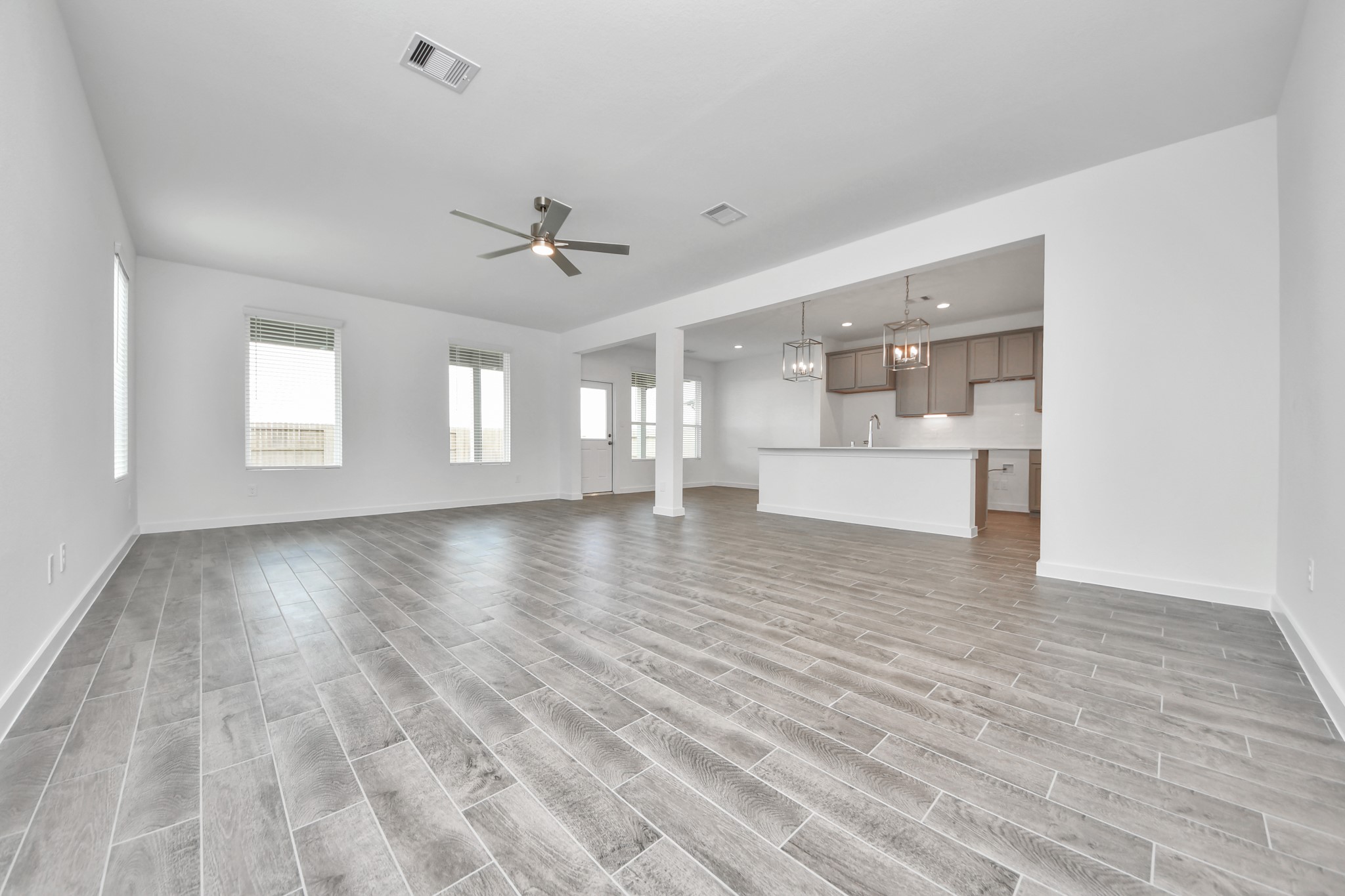 Relax and unwind in this inviting family room, illuminated by abundant natural light streaming in through tall windows, complemented by high ceilings and stunning flooring. Stay comfortable year-round with the gentle breeze from the ceiling fan, creating the perfect atmosphere for family gatherings. Sample photo of completed home with similar floor plan. Actual colors and selections may vary.