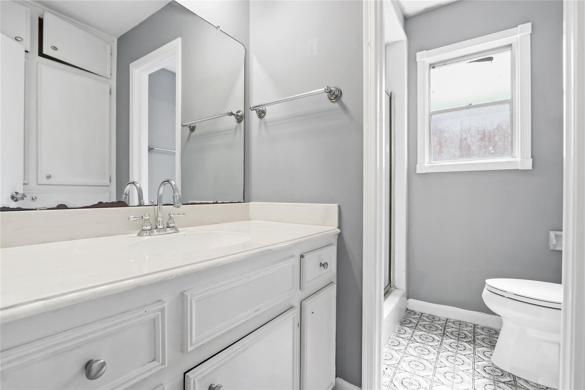 Primary ensuite bathroom featuring an extended vanity with ample cabinet space, a walk-in shower, and natural light.