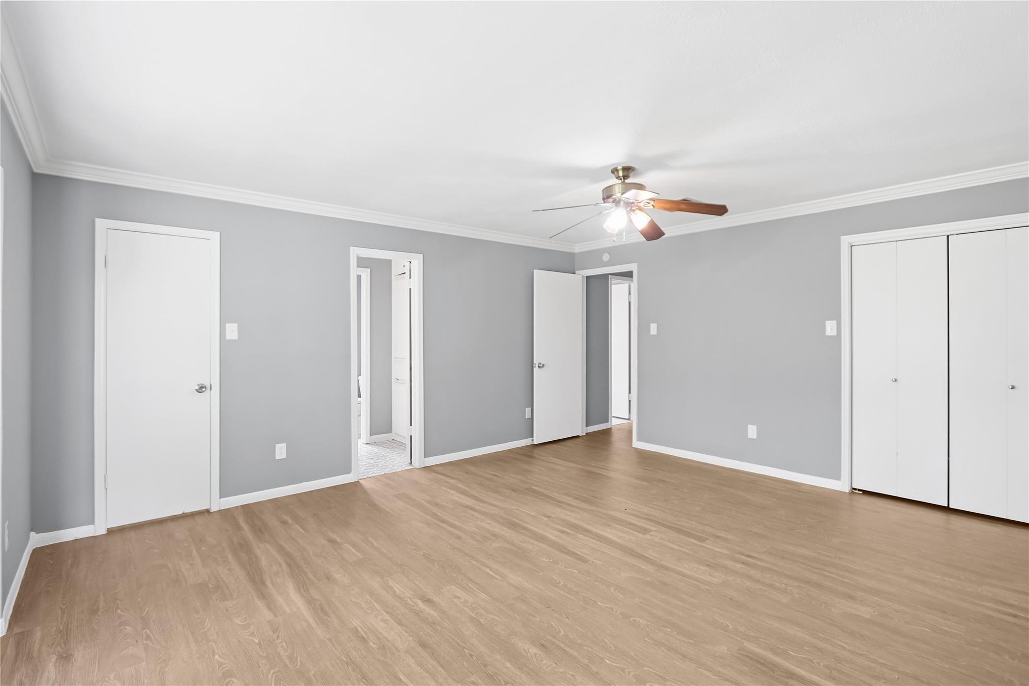 Head to the opposite side of the home and step into the spacious primary bedroom, featuring wood-look flooring, crown molding, ample closet space, and a private ensuite bathroom.