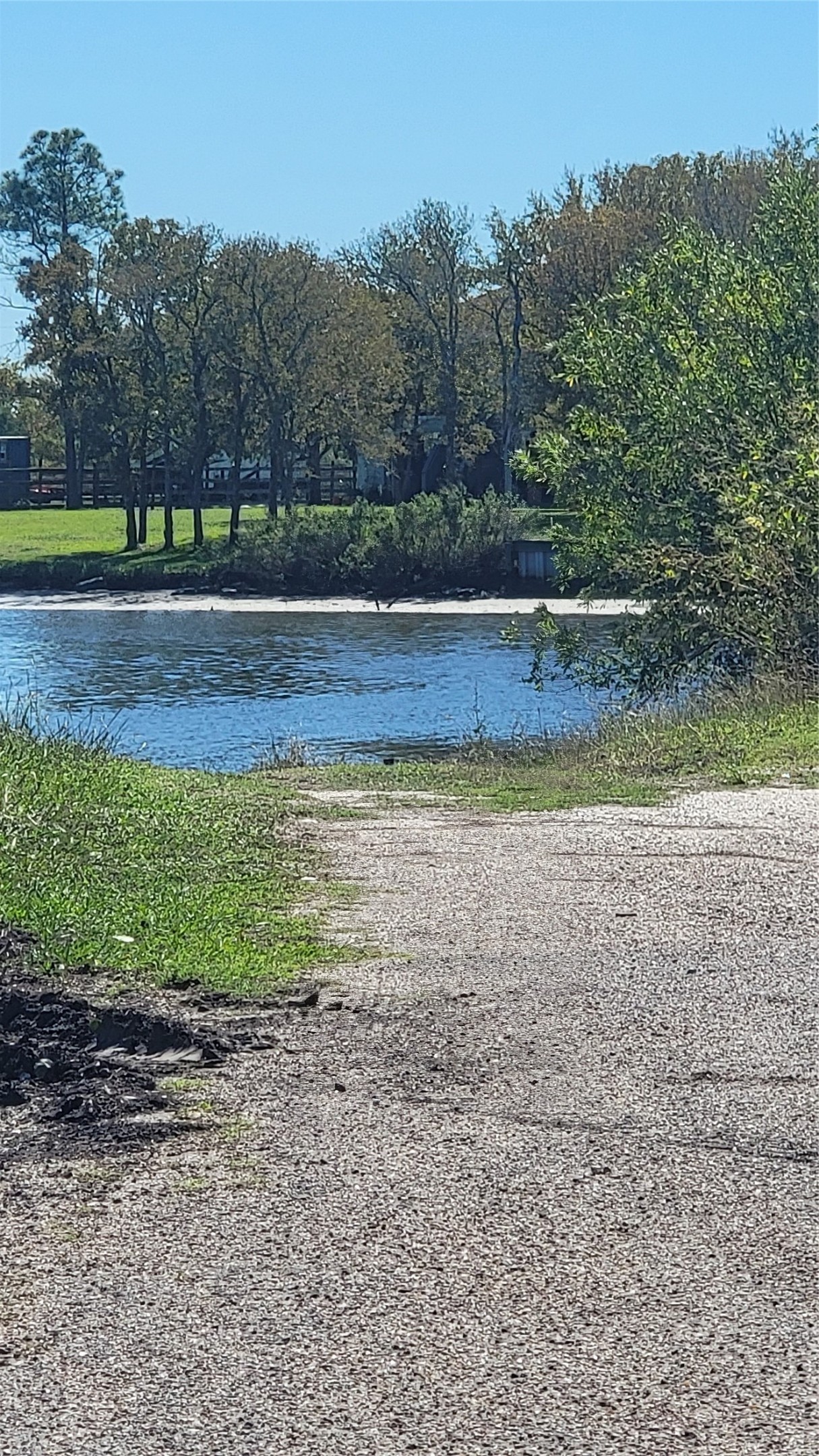 This photo showcases a serene waterfront view with a paved path leading to a peaceful body of water, surrounded by lush greenery and trees, perfect for nature lovers.