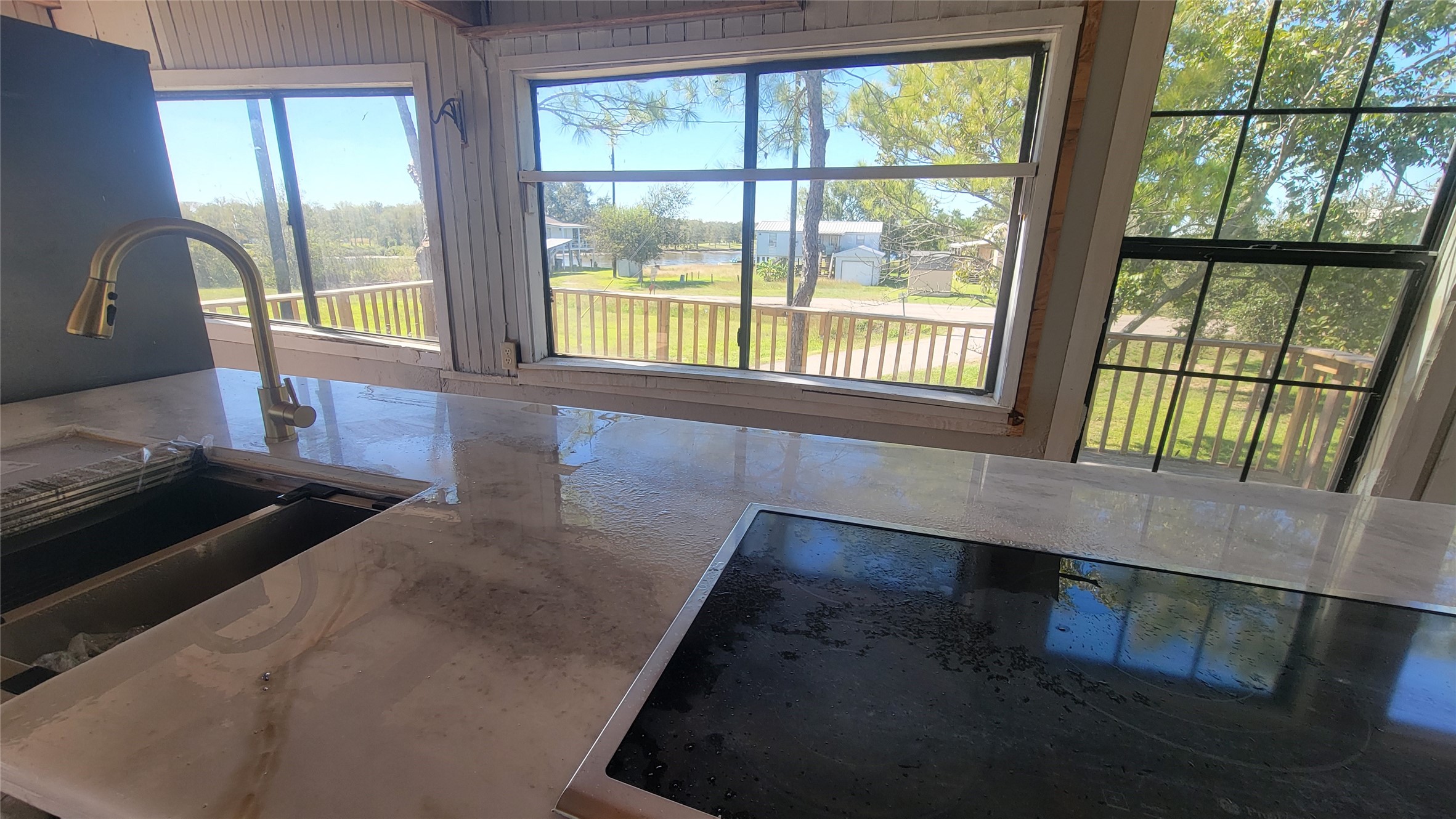 This photo showcases a kitchen with large windows offering a scenic view. The space features a modern countertop with an integrated sink and cooktop, creating a bright and inviting atmosphere.
