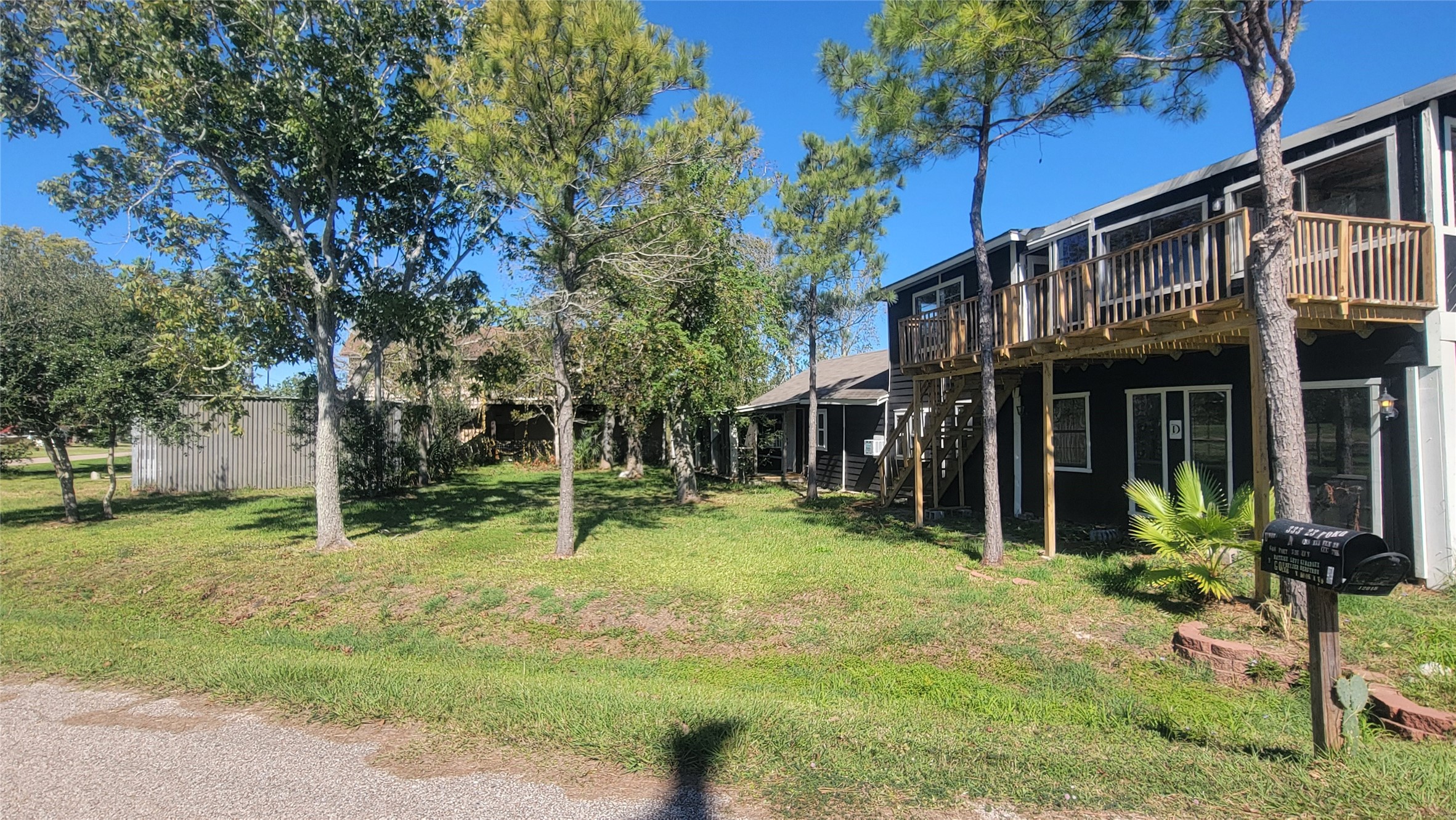 Charming two-story home with a wooden balcony, set amidst mature trees. The spacious yard offers plenty of greenery, providing a serene and private outdoor space. The property is located on a quiet street, perfect for peaceful living.