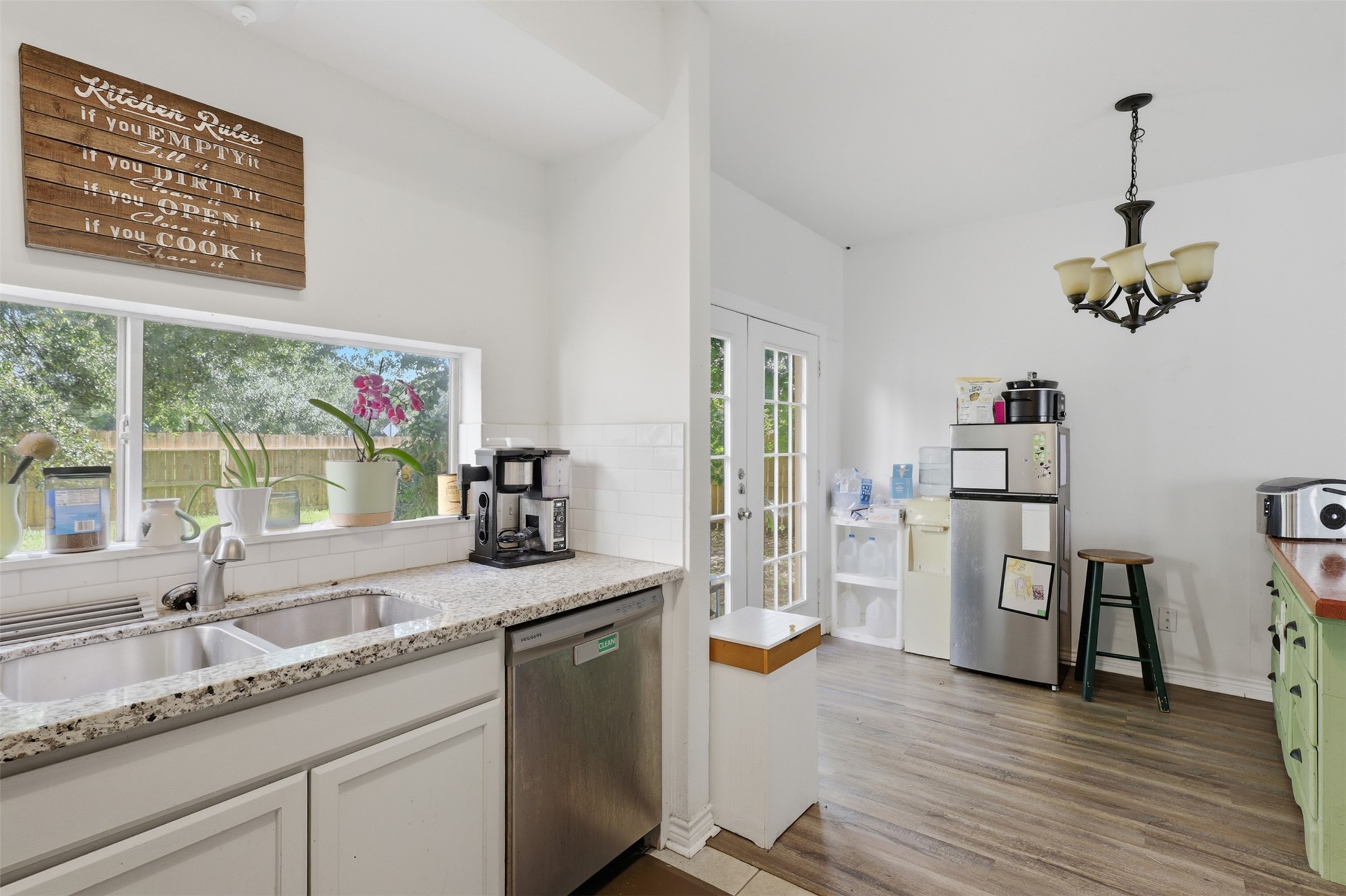 Under-mount sink positioned beneath a picturesque window, complete with full-sized dishwasher space and quick outdoor access for summer barbecues.