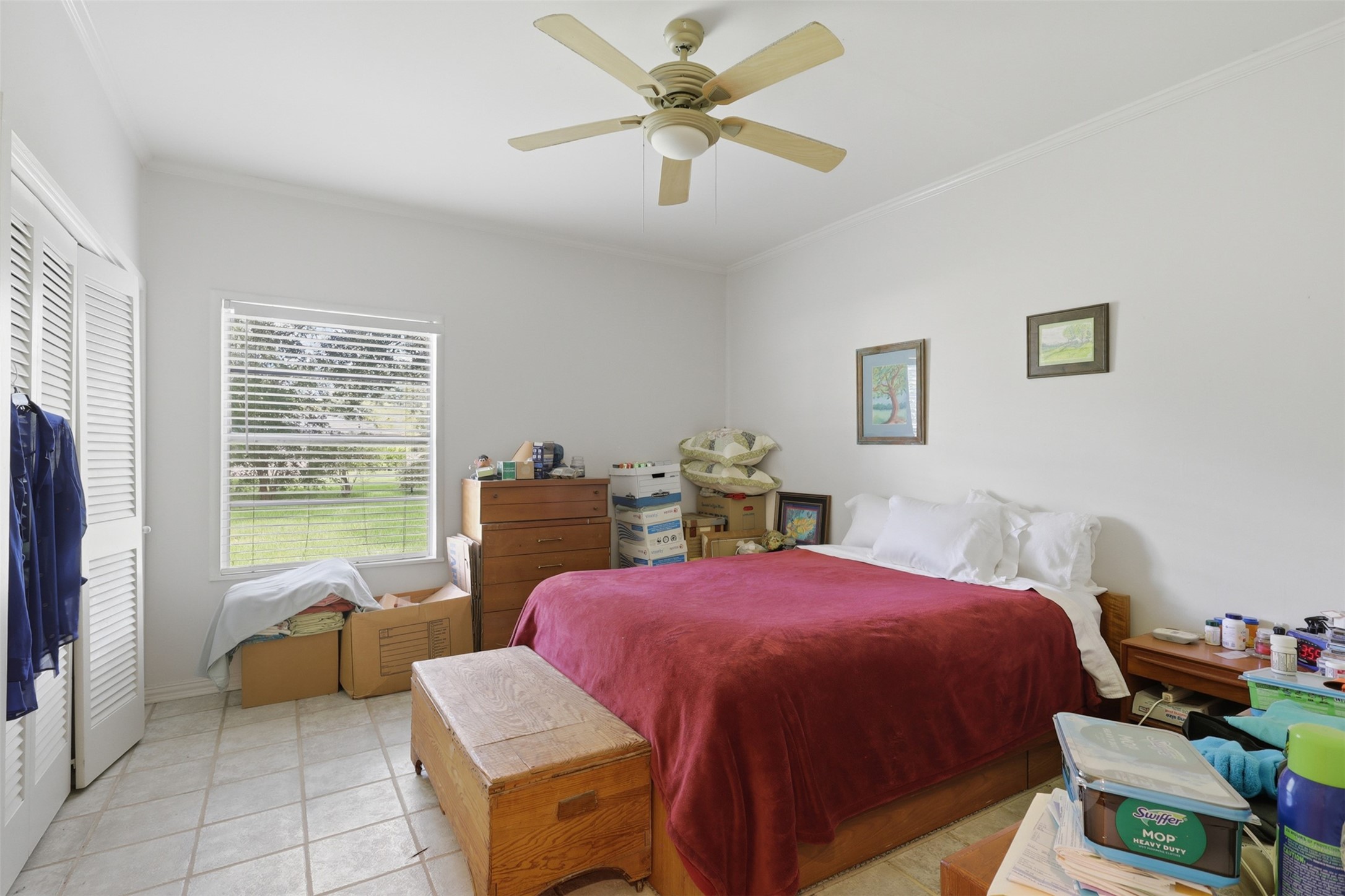 Low-maintenance tile flooring and a refreshing ceiling fan complement a bright bedroom layout, complete with generous closet space and peaceful views.