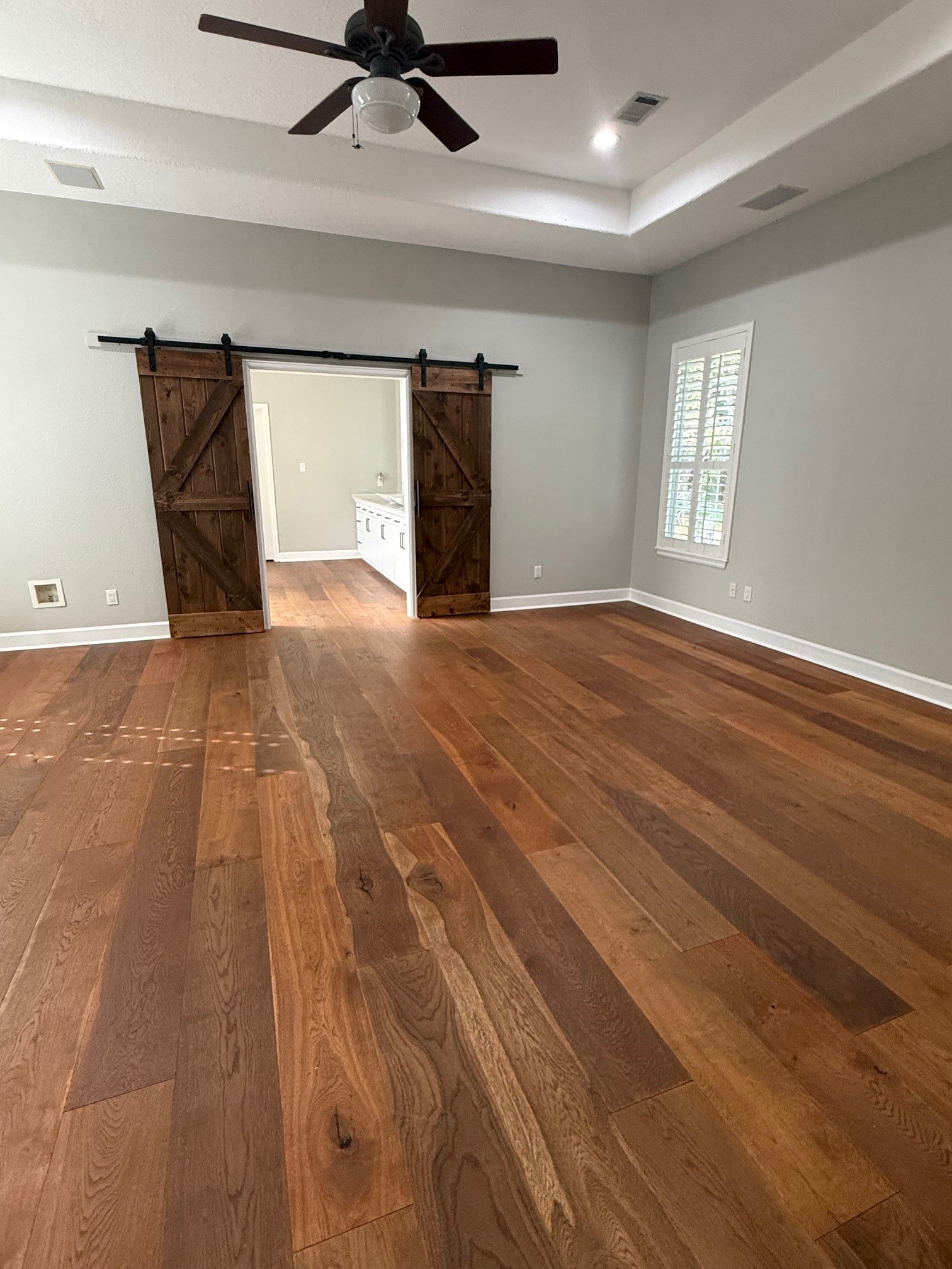 Spacious primary bedroom with barn doors to primary bath