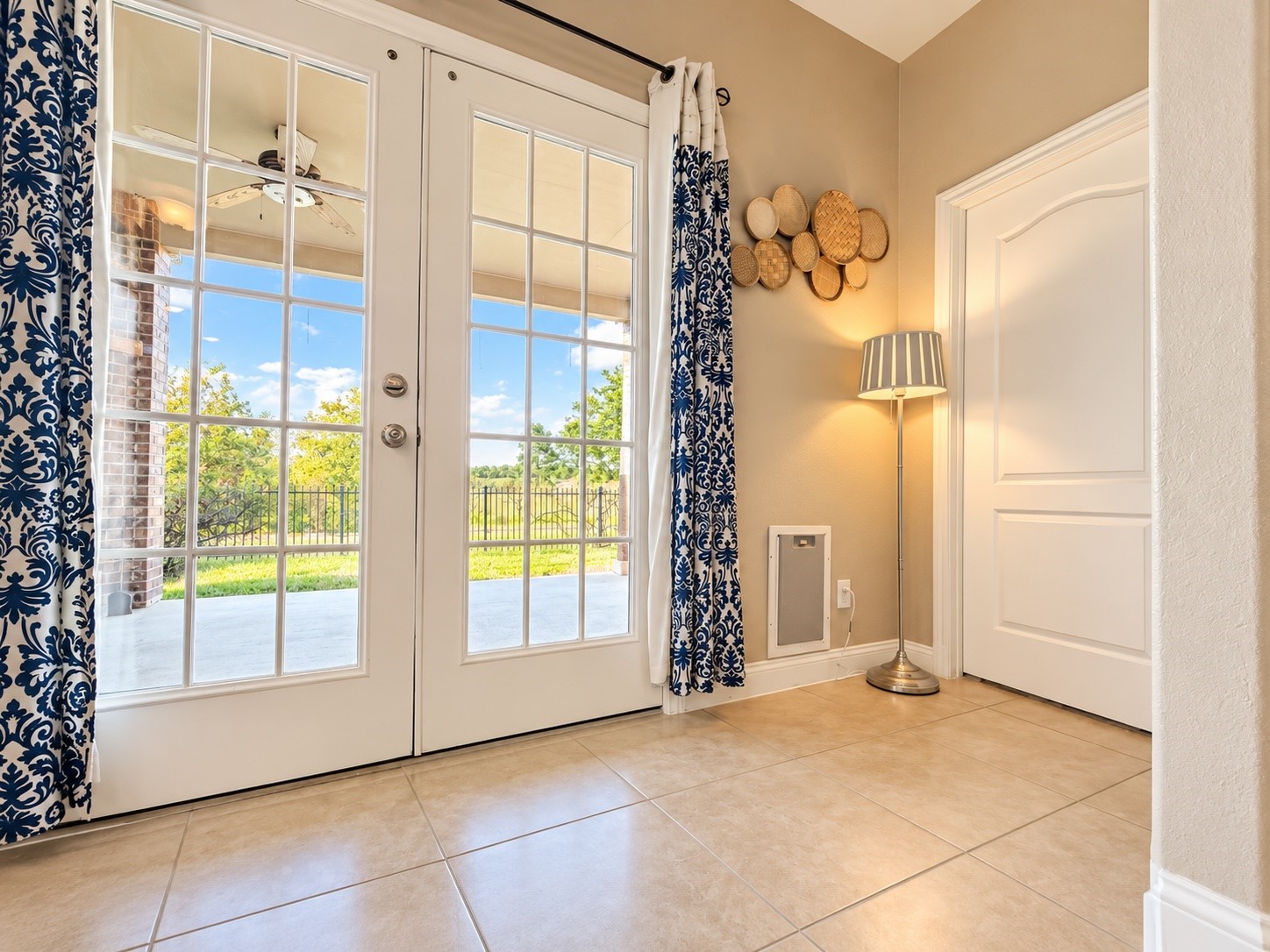 Beautiful French doors open wide to a covered outdoor living space featuring a cozy fireplace and spacious patio.