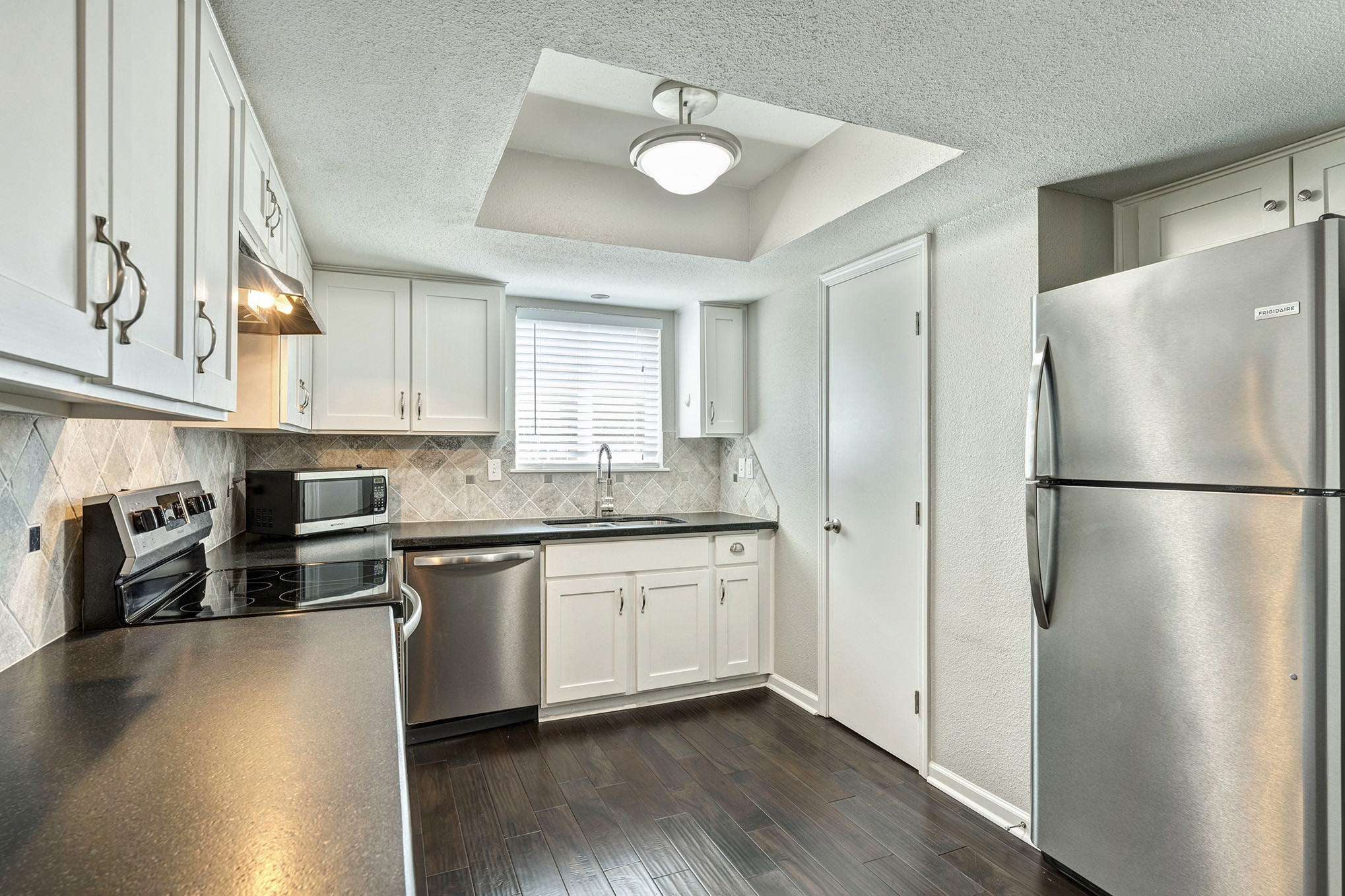 Granite kitchen offers stainless steel appliances including refrigerator and microwave plus pantry.