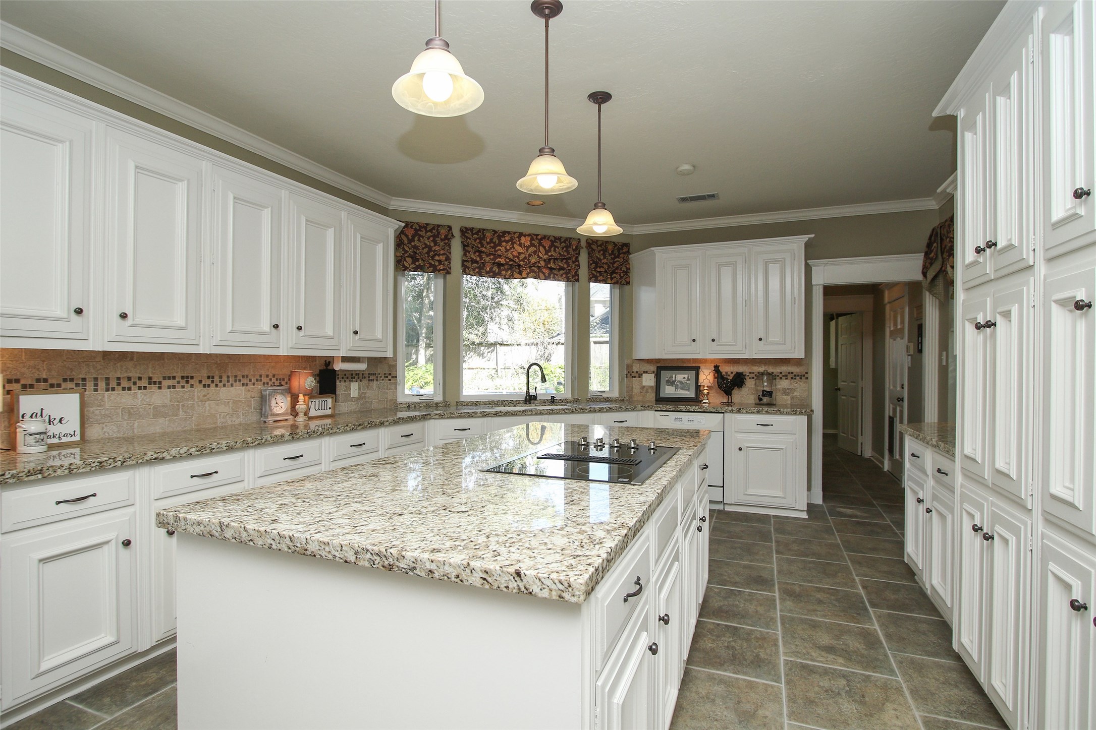 KITCHEN WITH LARGE ISLAND with granite counters and tumbled marble back splash.