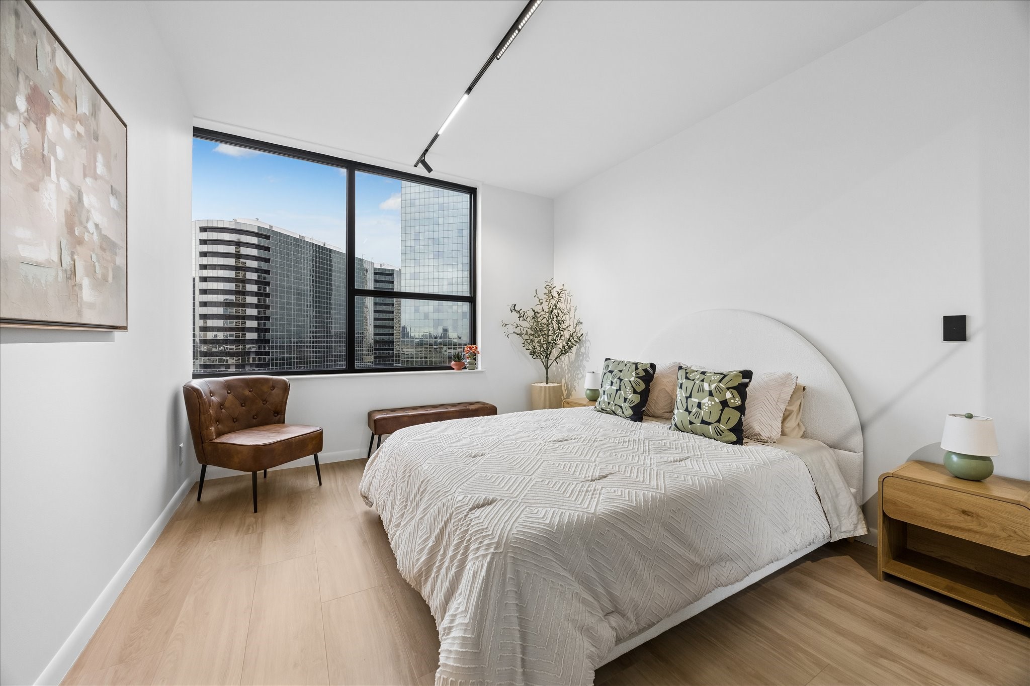 Broad window brings city views and natural light into the secondary bedroom.