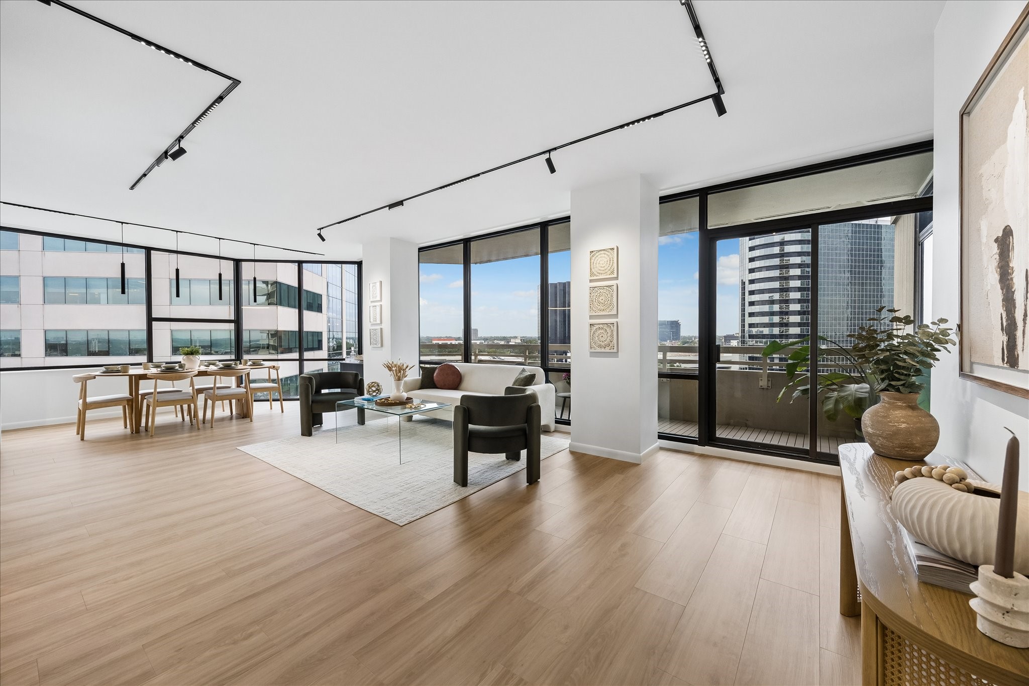 Expansive windows connect open living and dining areas with city views and balcony access.