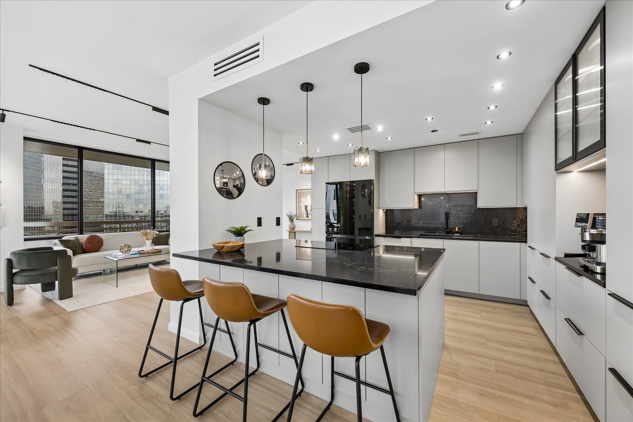 Kitchen island connects preparation space with the adjoining living areas. Marble-effect glass composite countertops and backsplash complement a Samsung four-door Flex refrigerator with remote app control. Kitchen island connects preparation space with the adjoining living areas. Marble-effect glass composite countertops and backsplash complement a Samsung four-door Flex refrigerator with remote app control.