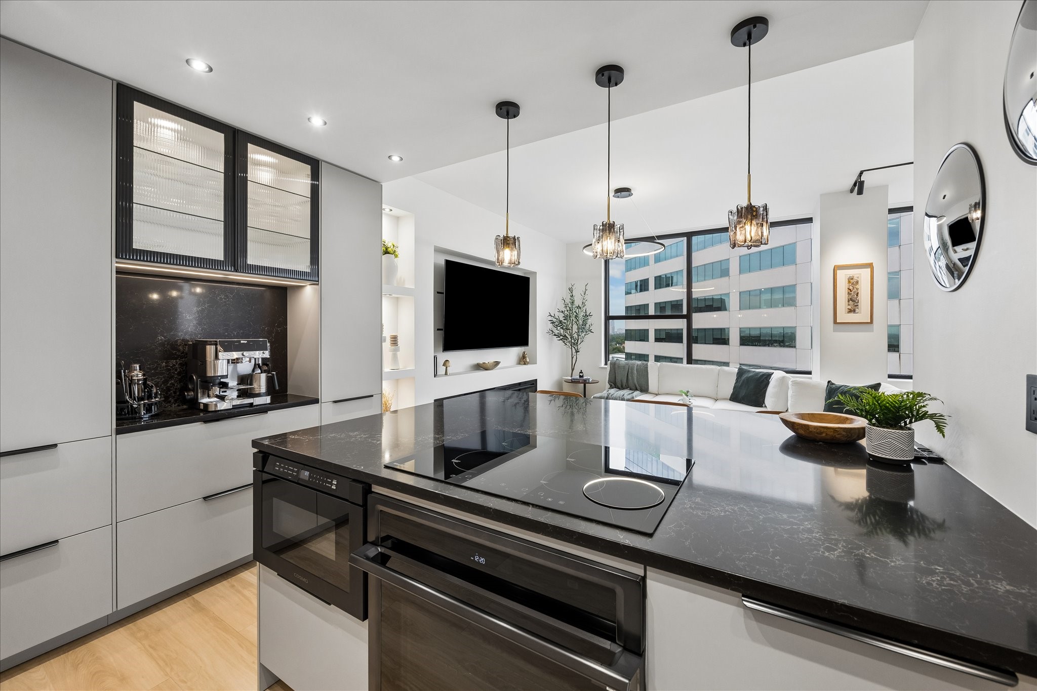 Induction cooktop, Samsung single oven with remote app control and built-in microwave drawer place cooking within the open kitchen. Marble-effect glass composite countertops and backsplash frame the coffee/bar nook.