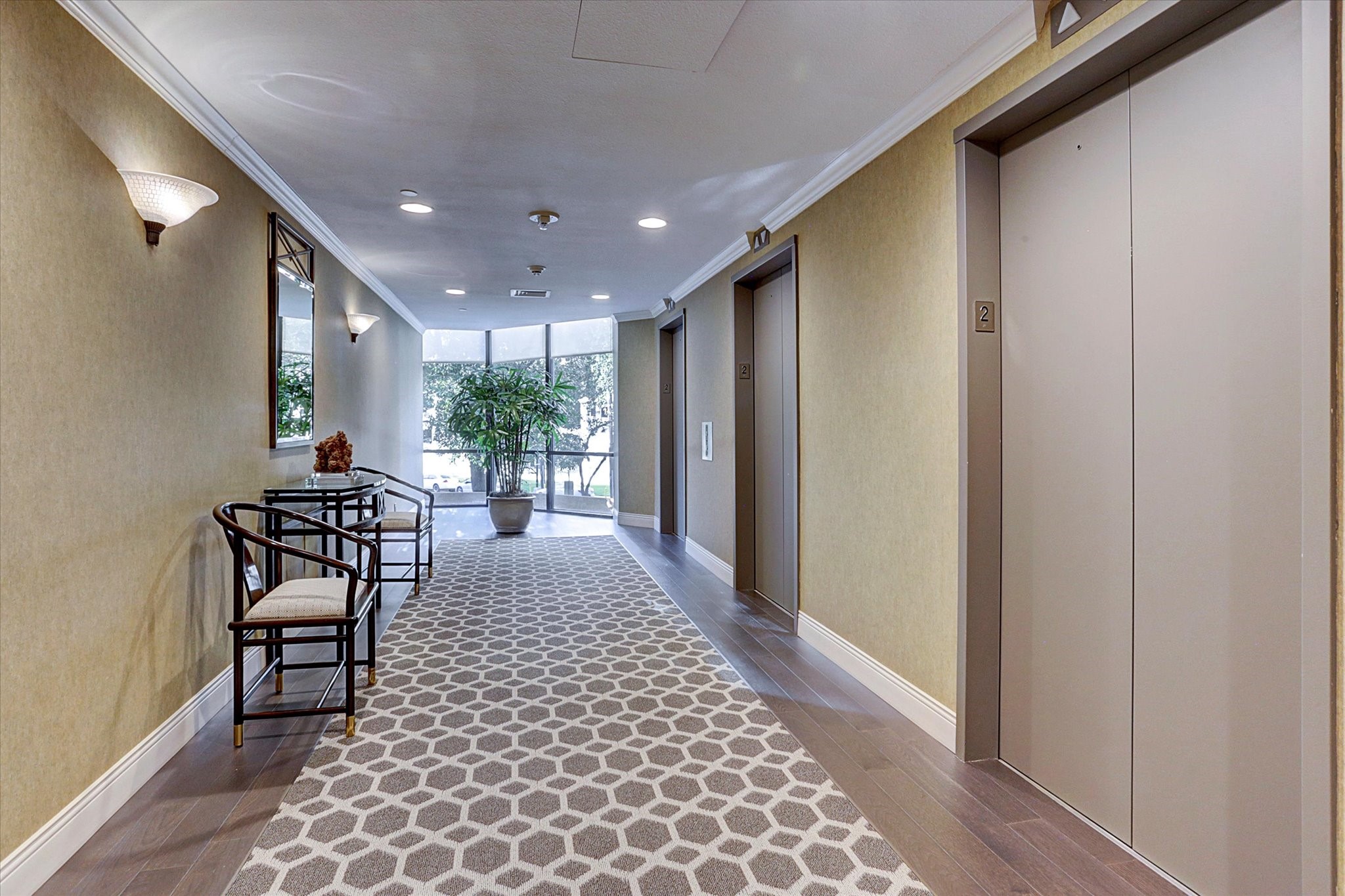 The elevator lobby features patterned carpeting, accent lighting and a seating area beside a large window, continuing the buildings welcoming common-area design.