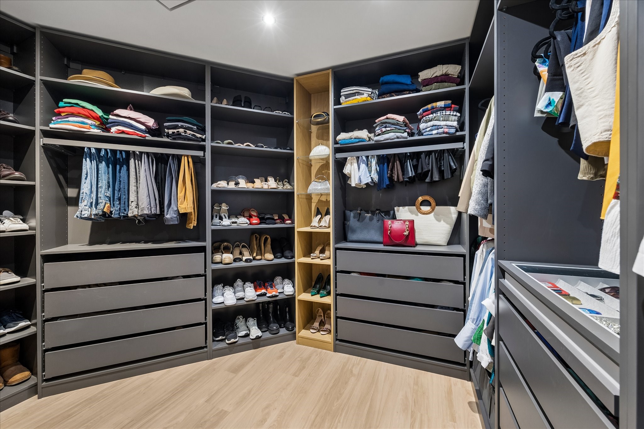 Fitted closet combines hanging space, drawers and open shelving around a central aisle.