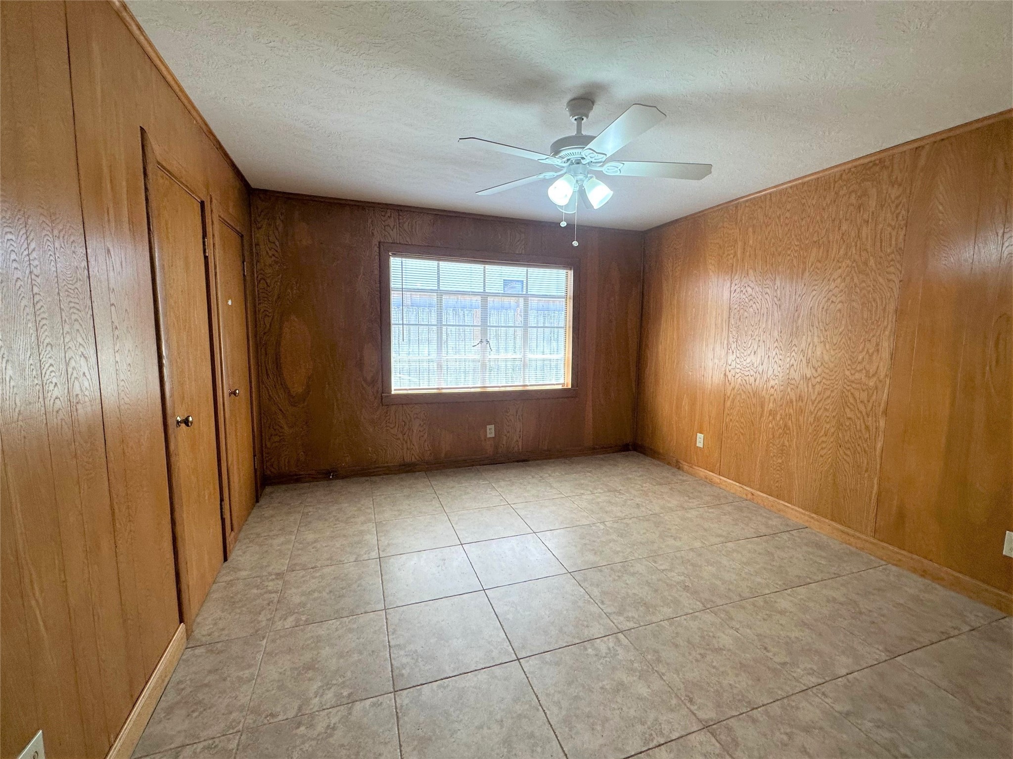 Nice-sized primary bedroom with large window, ceiling fan and tile floors.  No carpet in this house!