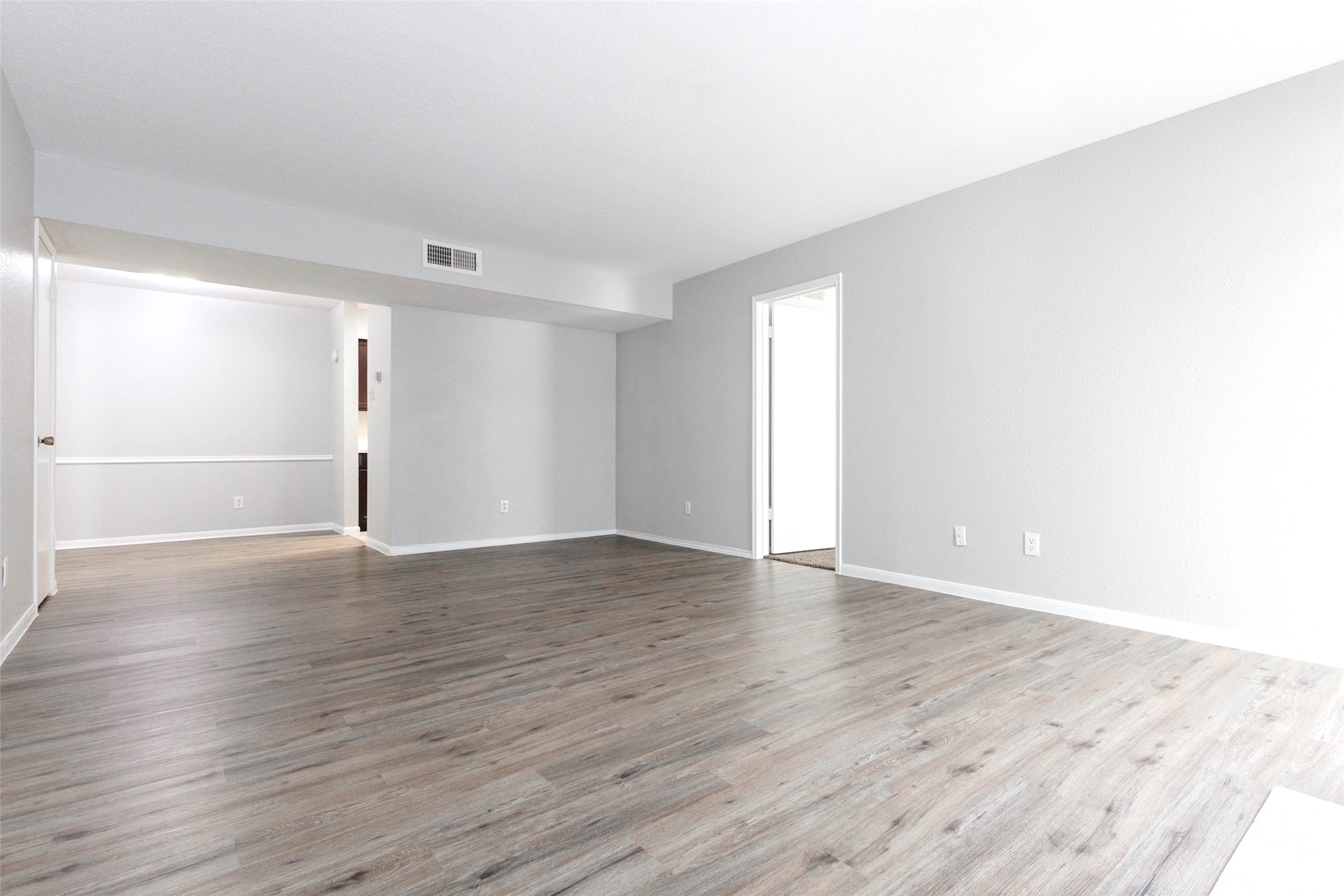 Spacious living area with attractive wood-look flooring, neutral finishes, and an open layout that allows flexible furniture placement.