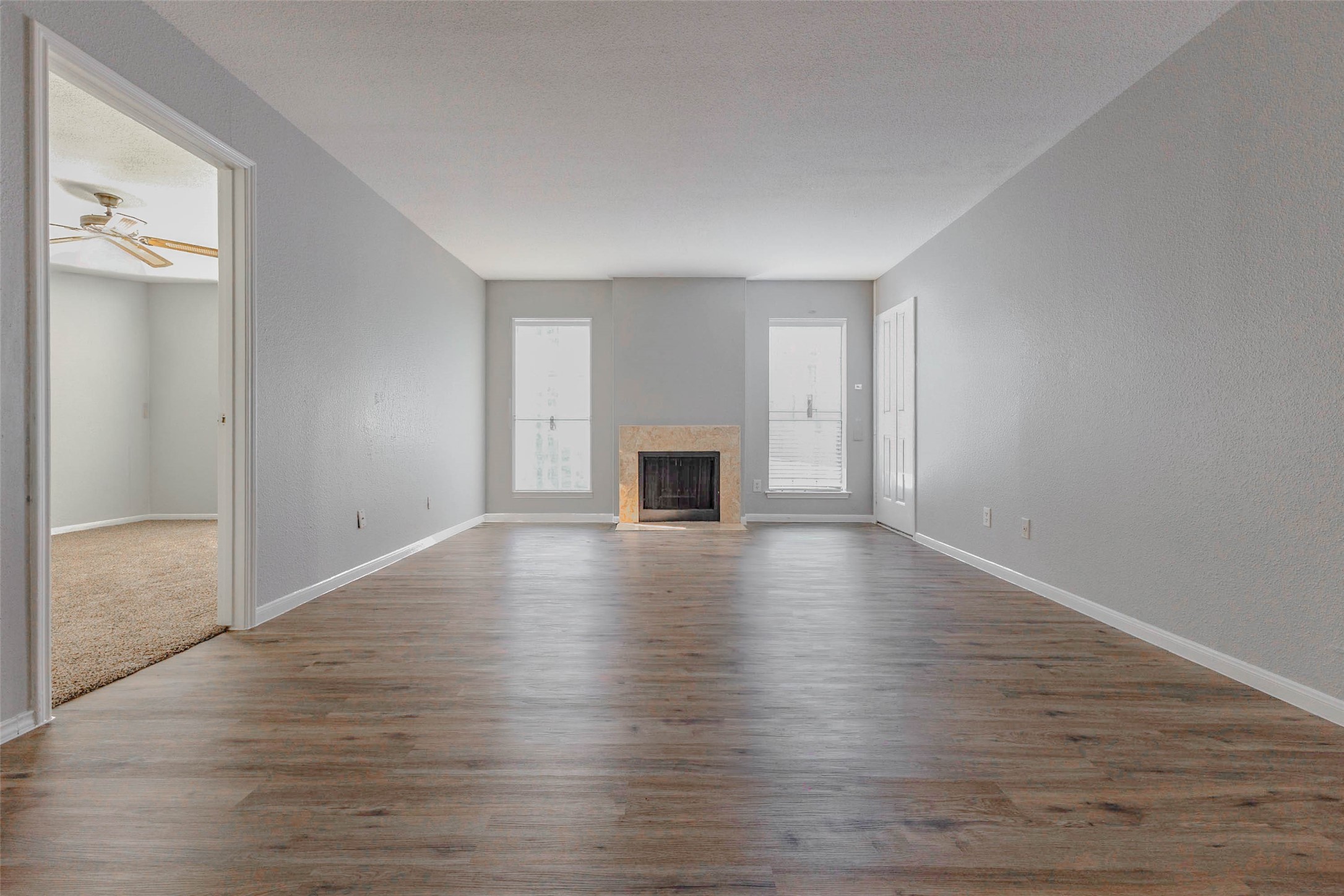 Expansive living room featuring a cozy fireplace, wood-look flooring, and plenty of room for comfortable seating and entertaining.