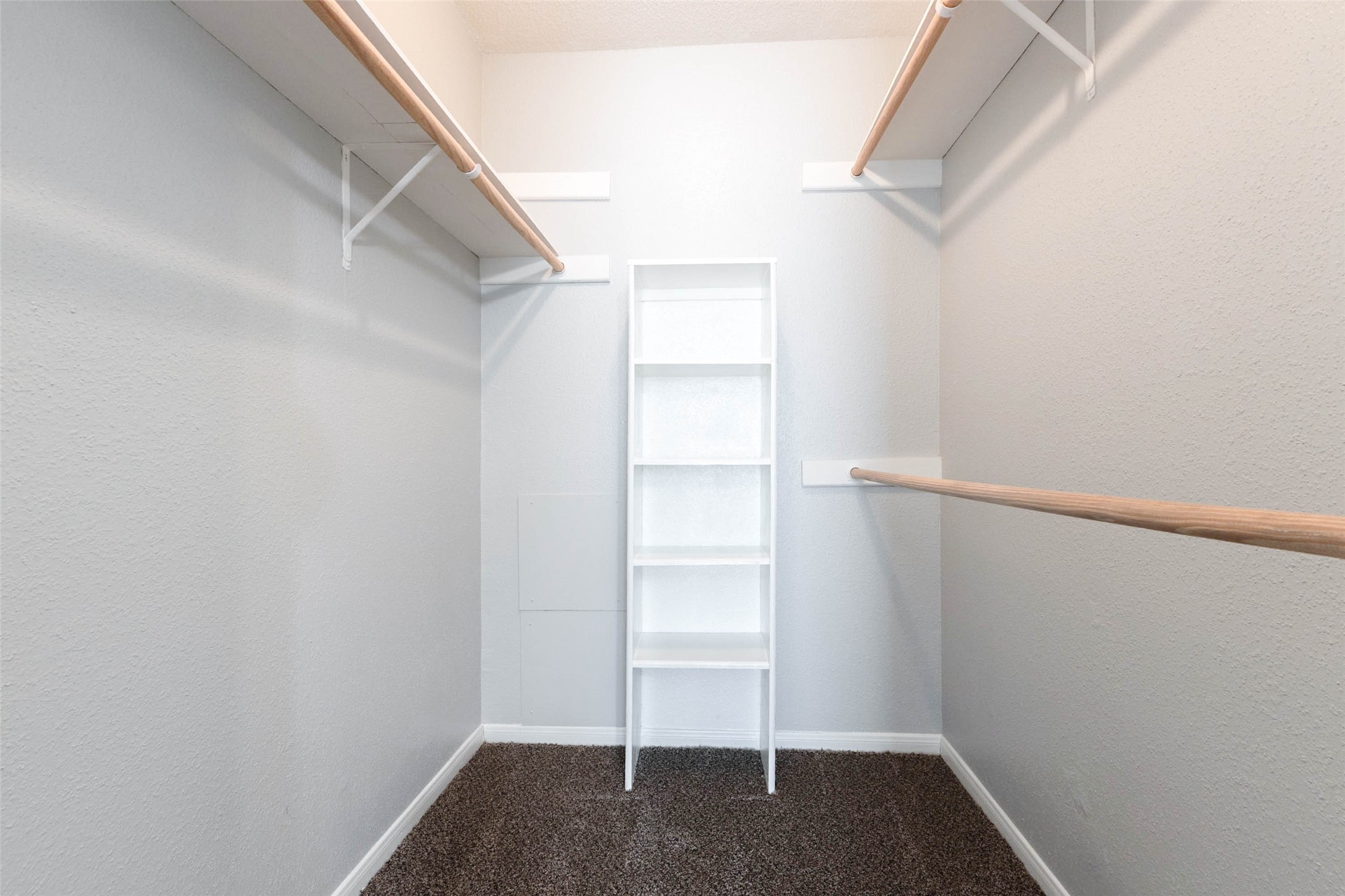 Spacious walk-in closet with built-in shelving, multiple hanging rods, and room to keep clothing and accessories organized.