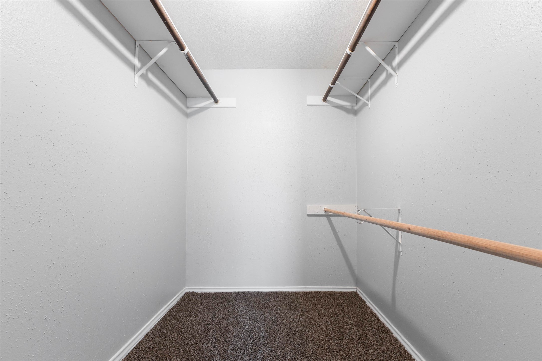 Generously sized walk-in closet with shelving and hanging rods on both sides for organized storage.