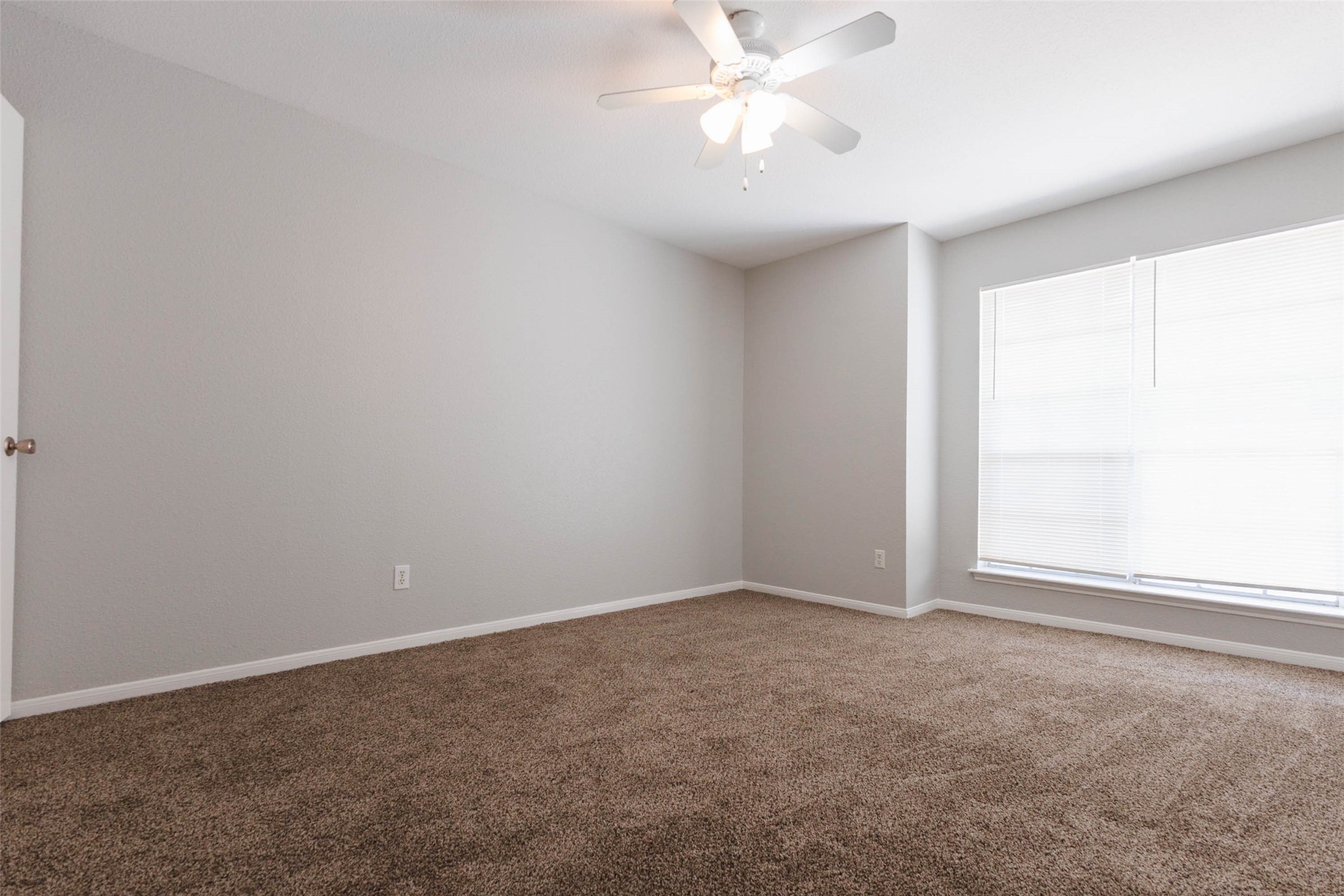 Additional bedroom view showcasing neutral finishes, comfortable proportions, and natural light from the window.