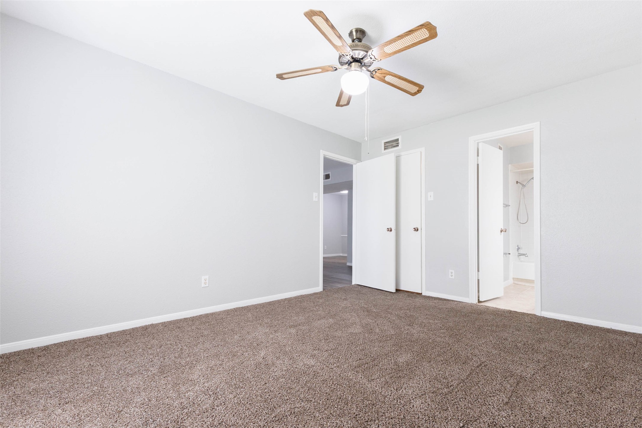 Alternate bedroom view highlighting the flexible layout, ceiling fan, and access to the bathroom and closet.