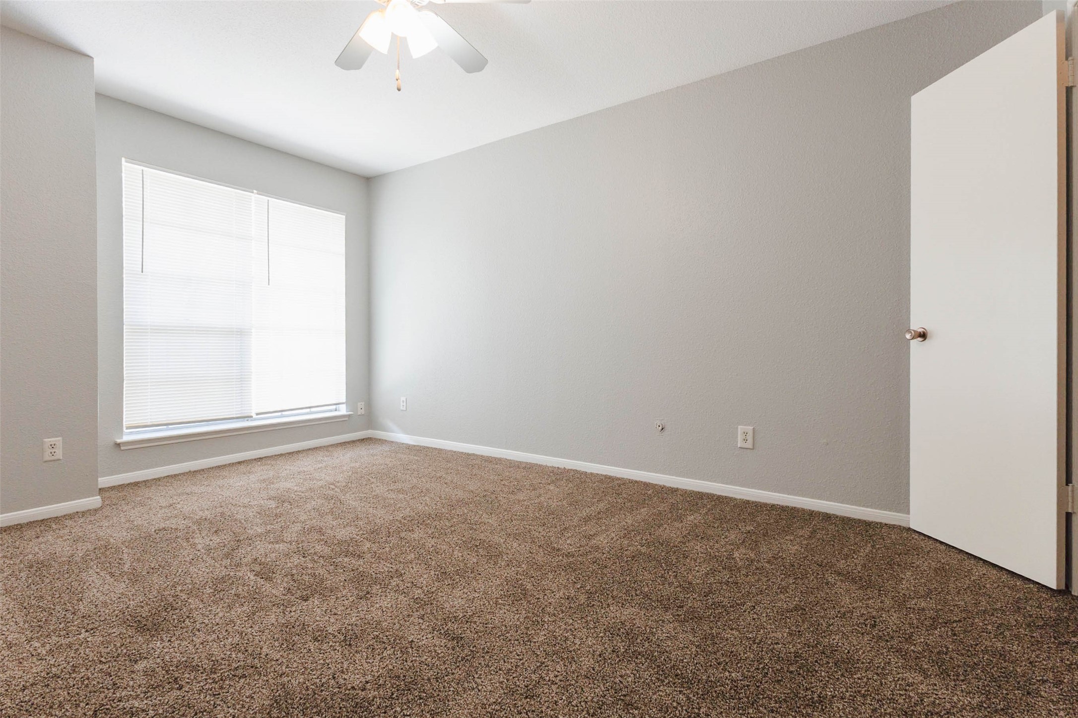 Another view of the bedroom highlighting its generous floor space, natural lighting, and versatile furniture arrangement options.