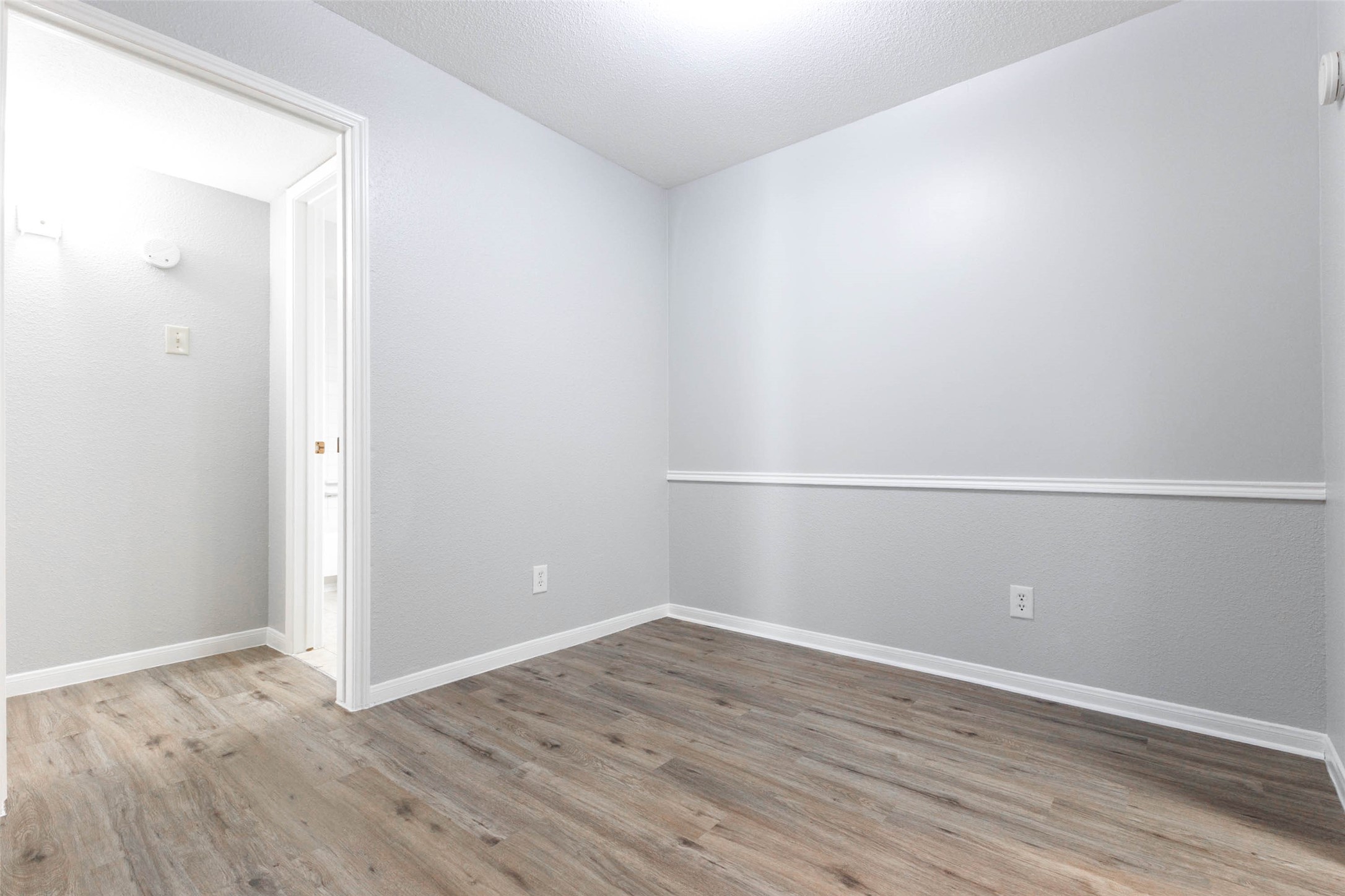 Separate dining space with wood-look flooring and chair rail detailing, offering flexibility for dining or a home workspace.