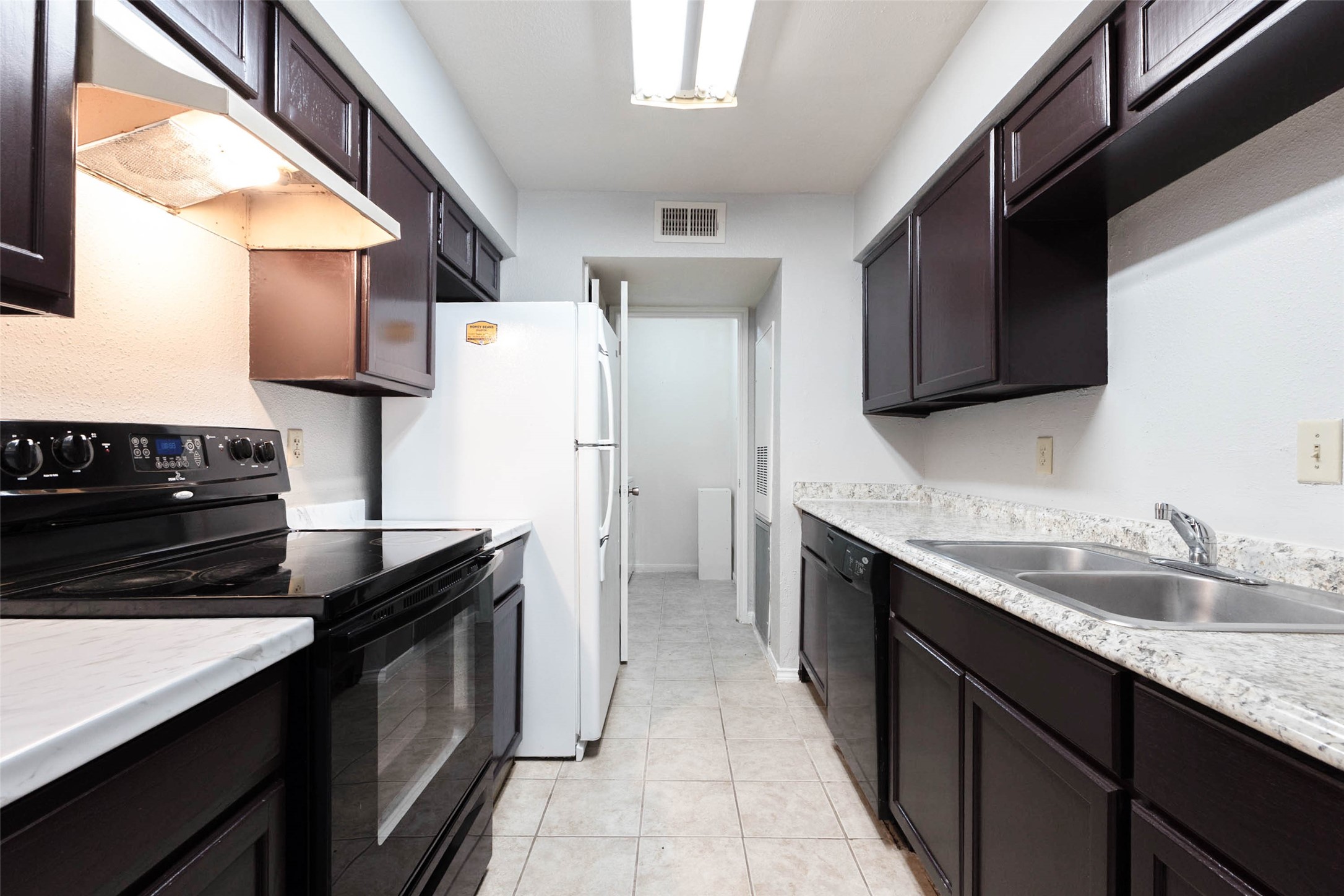 Galley-style kitchen with cabinetry on both sides, ample countertop workspace, and refrigerator, range, and dishwasher.