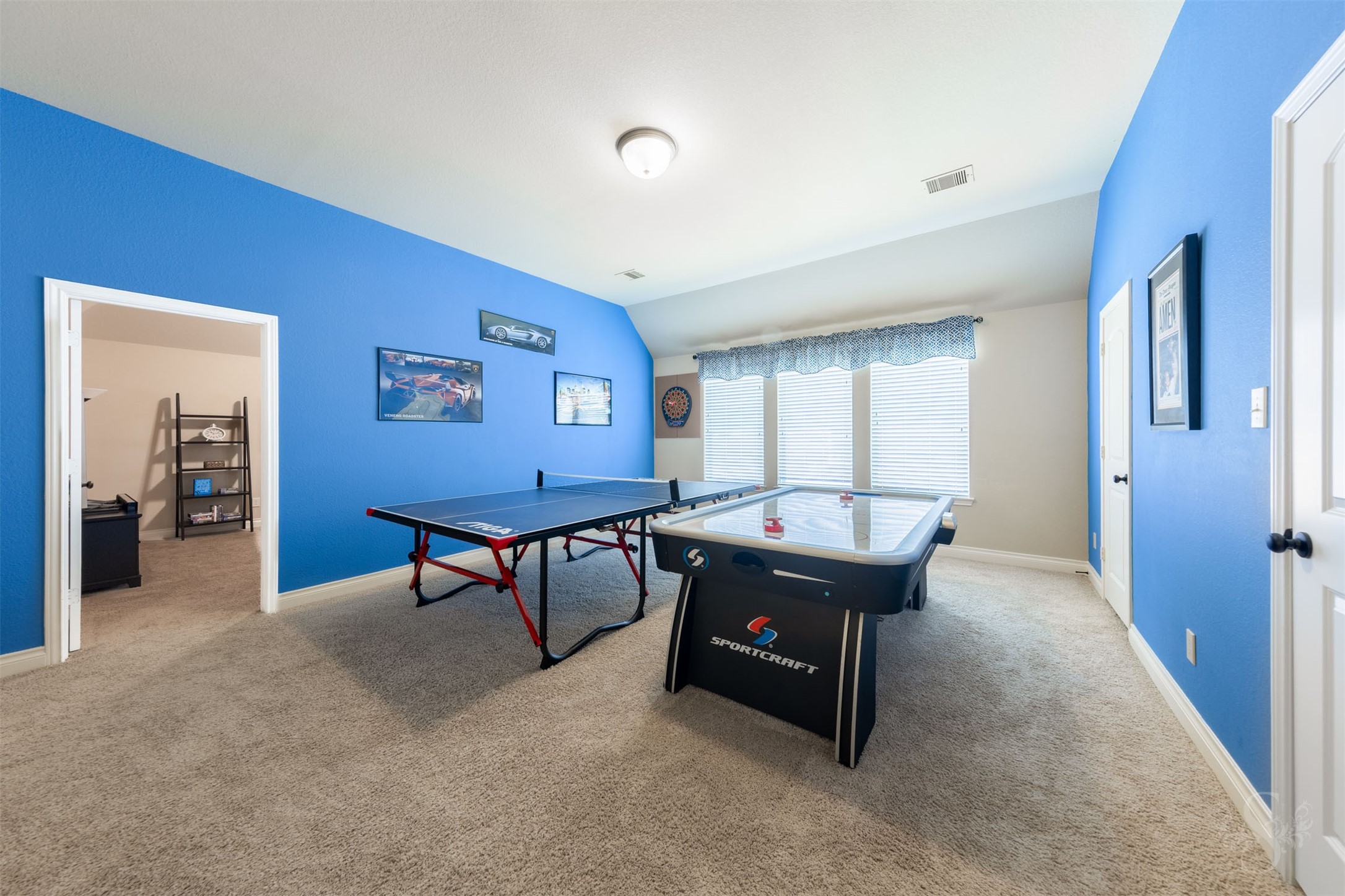 The expansive upstairs game room offers generous space for table tennis, air hockey and friendly competition. A wall of windows brightens this inviting gathering place, ready for hours of family fun.