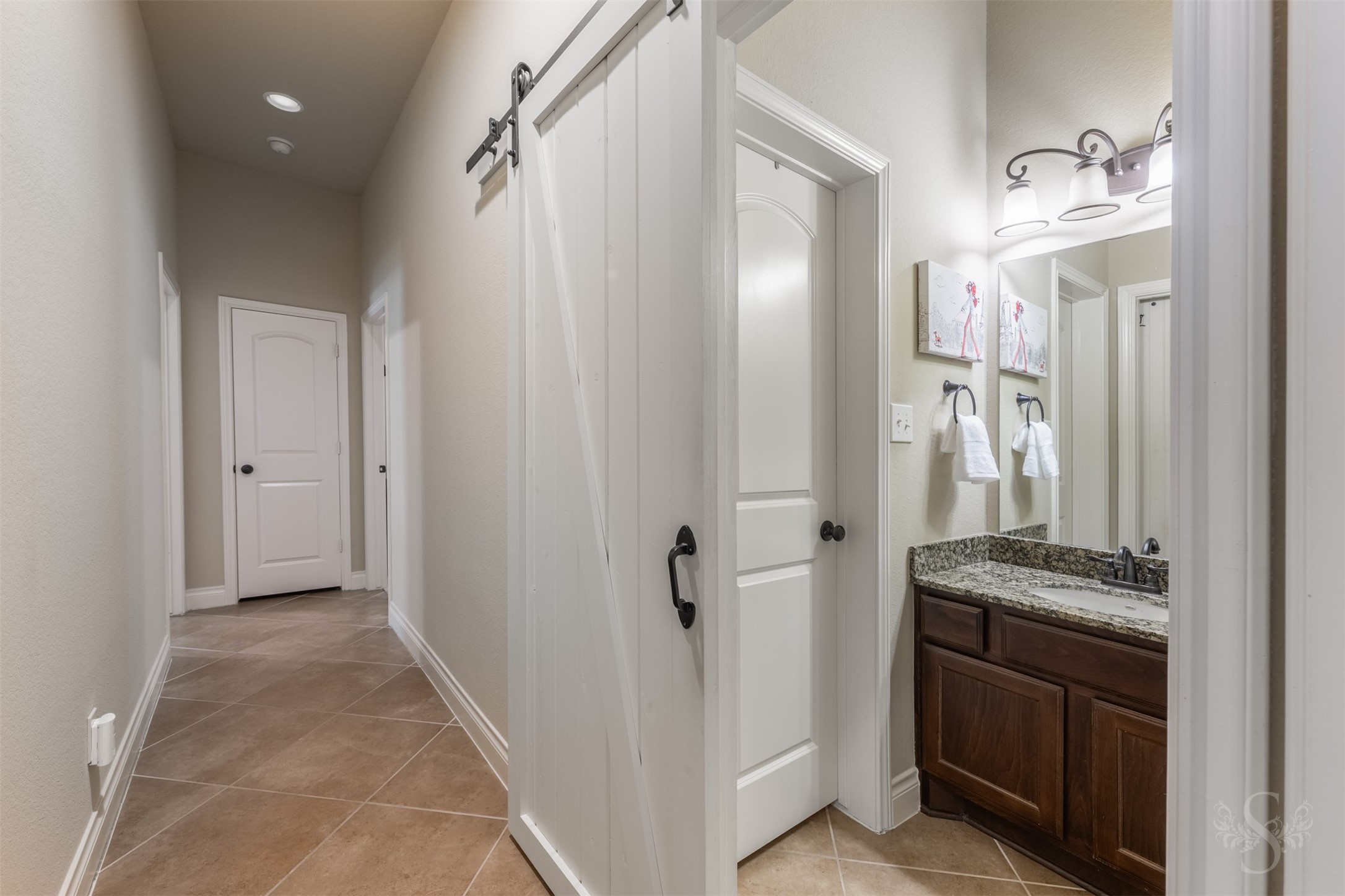 A sliding barn door adds character to the hallway and offers a stylish way to close off the adjoining bath. A granite vanity with richly stained cabinetry continues the homes elegant finishes.
