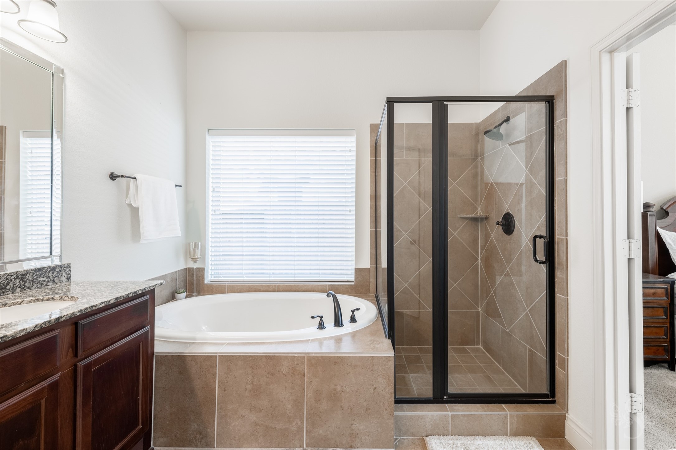 Unwind with a leisurely soak in the garden tub, nestled beneath a large window in the primary bath. A separate glass-enclosed shower and generous granite vanity complete this comfortable personal retreat.