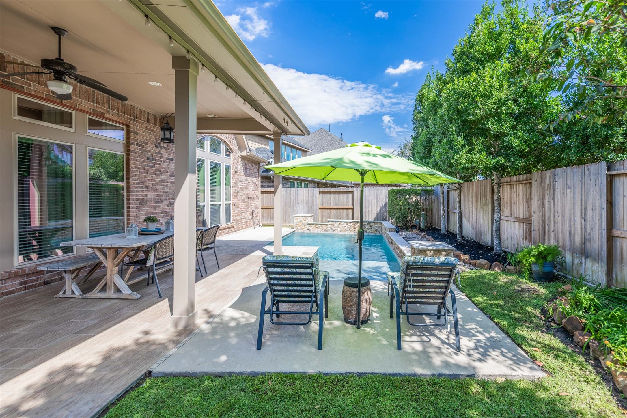 Enjoy a refreshing swim before settling into a favorite lounge chair in this beautifully landscaped backyard oasis. Mature trees and lush garden beds create a picturesque setting for leisurely afternoons by the pool.