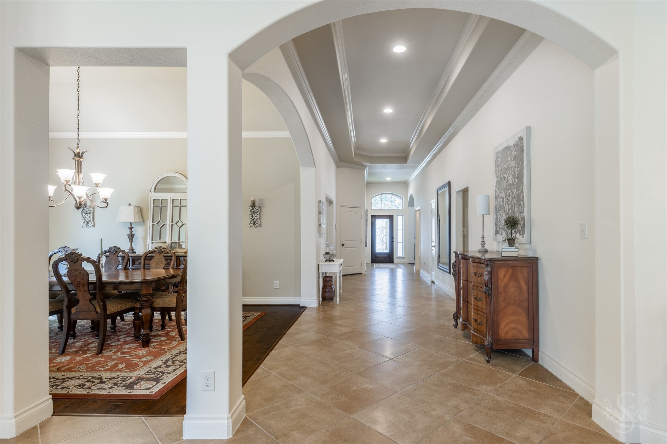 Graceful archways frame the formal dining room and extended entry, highlighting the architectural beauty that carries throughout the home. An elongated tray ceiling with crown molding and recessed lighting adds an exquisite finishing touch to this welcoming passage.