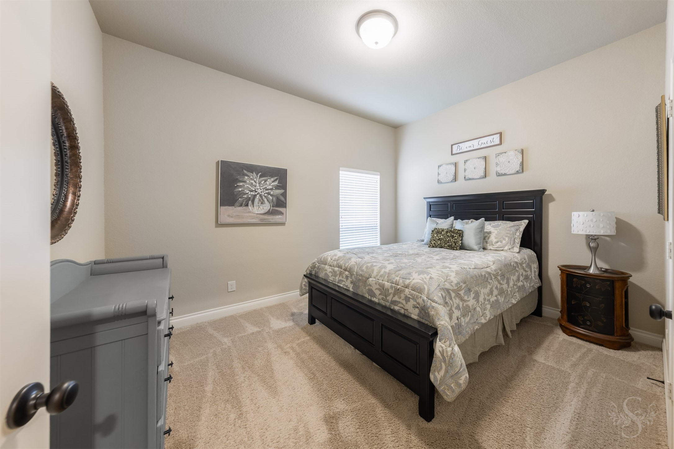 This spacious secondary bedroom offers a peaceful retreat with soft carpeting and a warm, neutral palette. Generous wall space allows for a variety of furniture arrangements, with room to create a comfortable reading or study area.